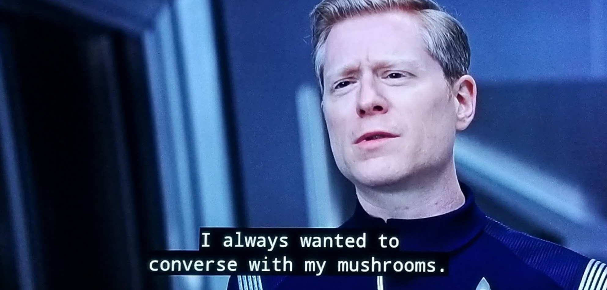 Star Trek Discovery scene. Pictured is Paul Stammets (Adventures in Babysitting). He's in a crisp blue uniform, on a starship, and looking wistful. Closed caption reads, "I always wanted to converse with my mushrooms."