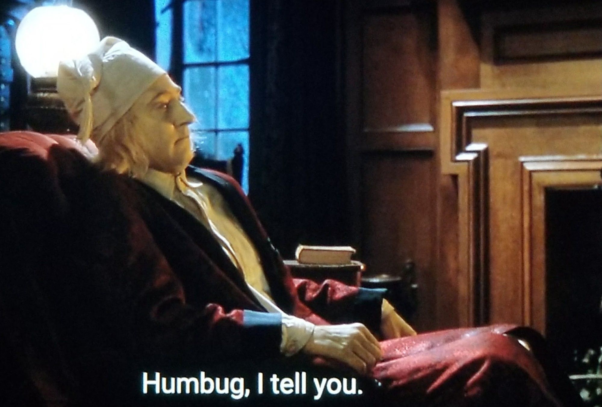 Data sits in a cozy chair, in an older house at night, presumably by a fire. There's a orb/night light behind him. He's wearing robe & pajamas and a long night cap like the one Scrooge always wears in the four thousand hundred versions of Christmas Carol available in popular media.  
Closed caption reads, "Humbug, I tell you."