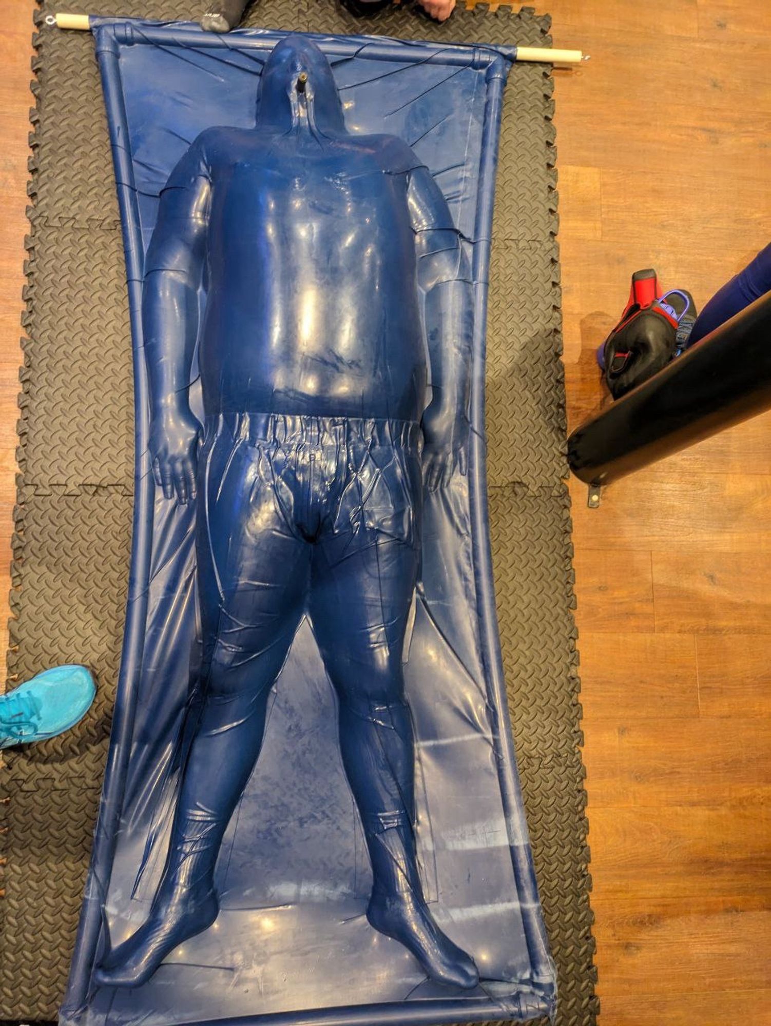 Aerial shot of the whole body in blue vac rack; air removed clearly showing the tracksuit bottoms and t shirt