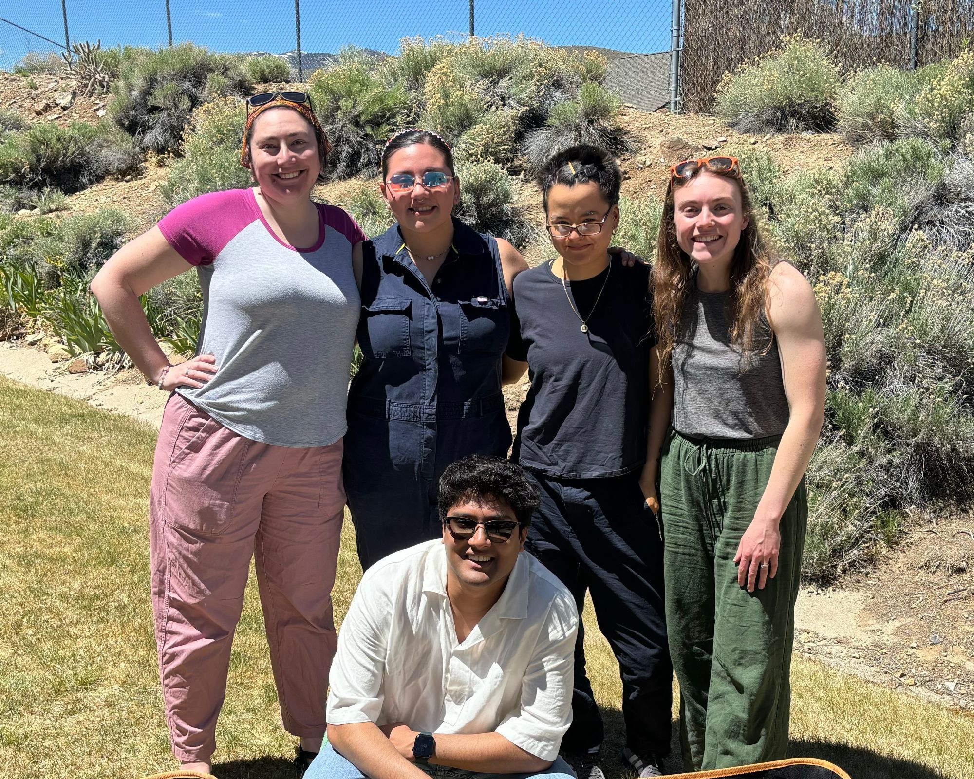 5 graduate students pose outside.