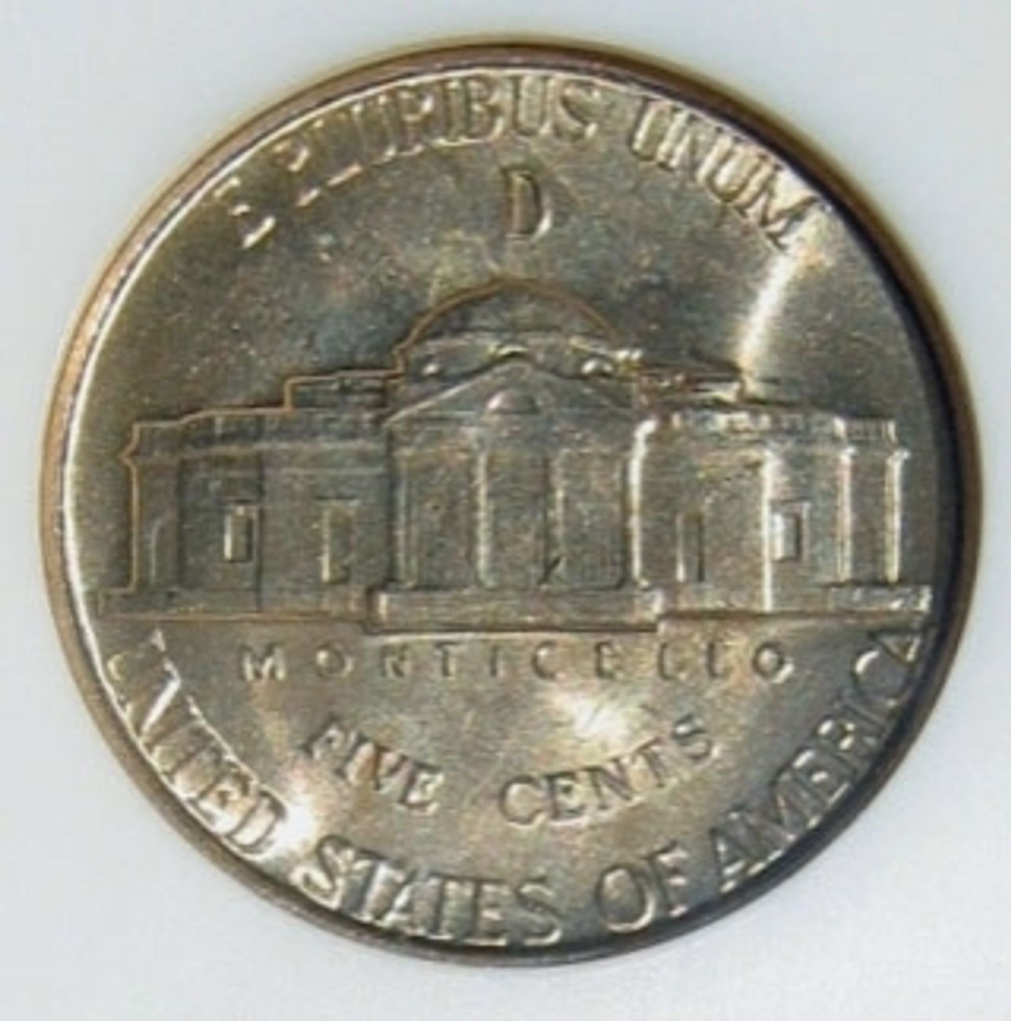 A US "war nickel, identifiable by its unusual color and the mint mark located above Monticello on the reverse (as opposed to on the front). Since nickel was needed as a component for armor plate, the composition of the 5-cent nickel piece* was temporarily changed from 75% copper, 25% nickel to 56% copper, 35% silver and 9% manganese.

*The official name of "that coin with Jefferson on it", as during various periods of US history there have been five-cent silver pieces ("half dimes") and three cent nickel-pieces (useful when that was the price of a first-class stamp).