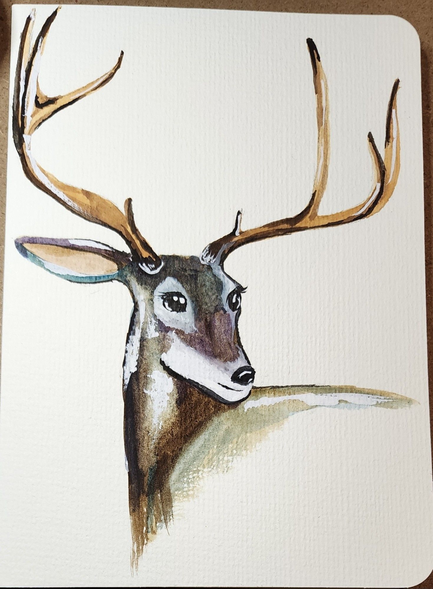 The watercolor painting of a deer with very large antlers. He is standing facing the left but his head is turned to the right.