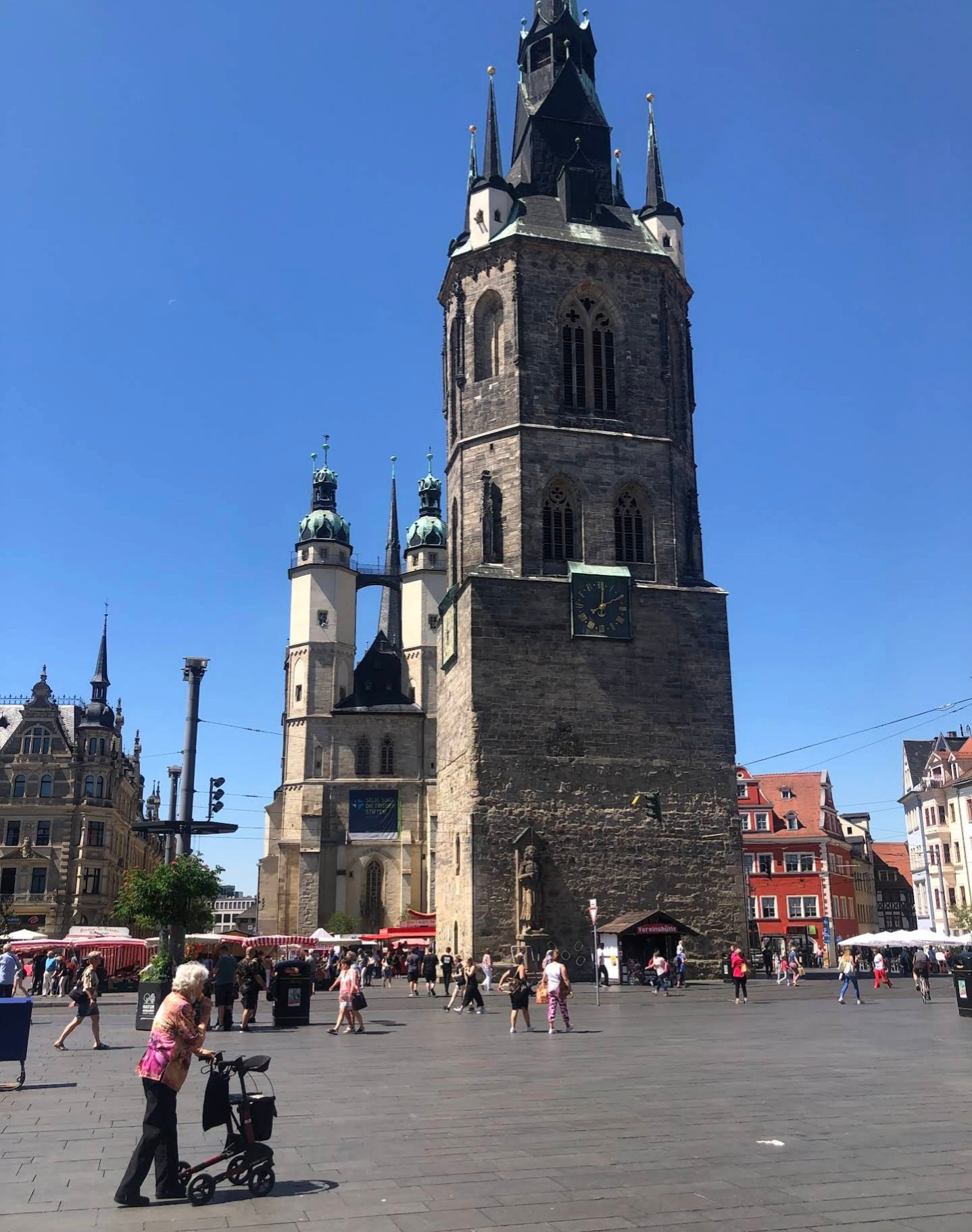 Roter Turm, Halle(Saale) by Nithu Sira from Google Maps, 2023. Few people milling around a high tower. Old woman in a walker, in foreground.