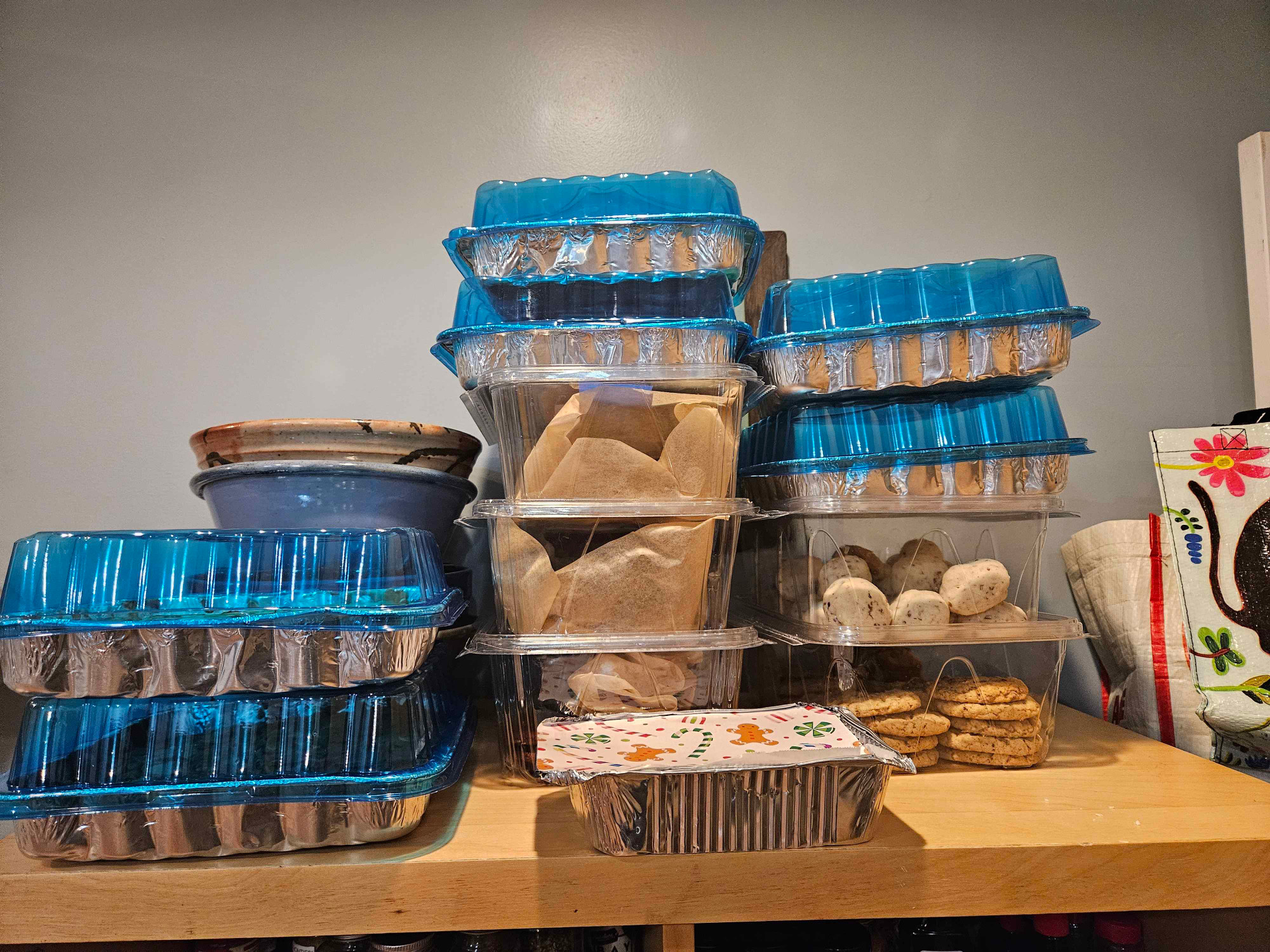 10 foil and plastic containers of various cookies stacked on a shelf.