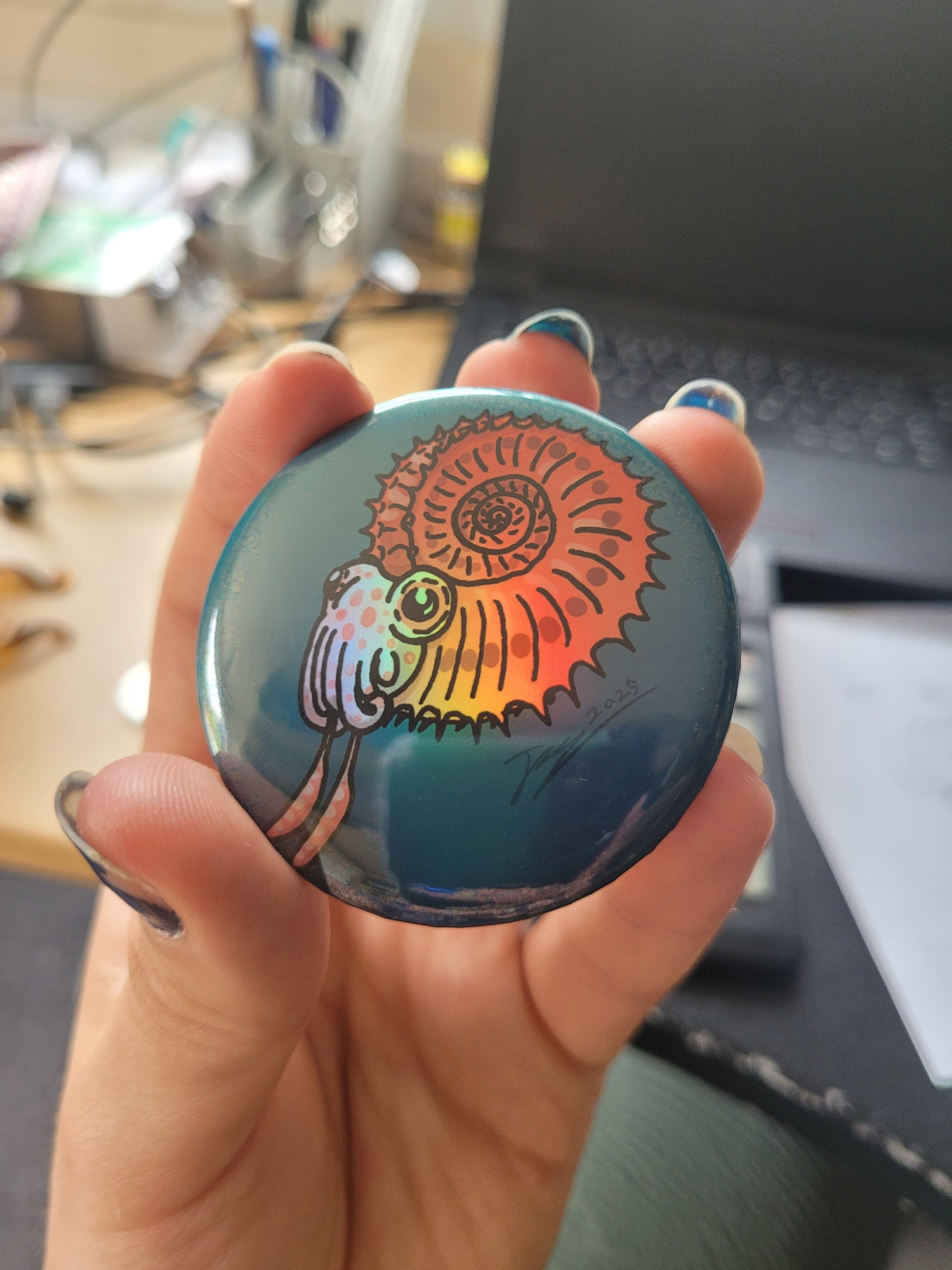 An iridescent baby ammonite badge