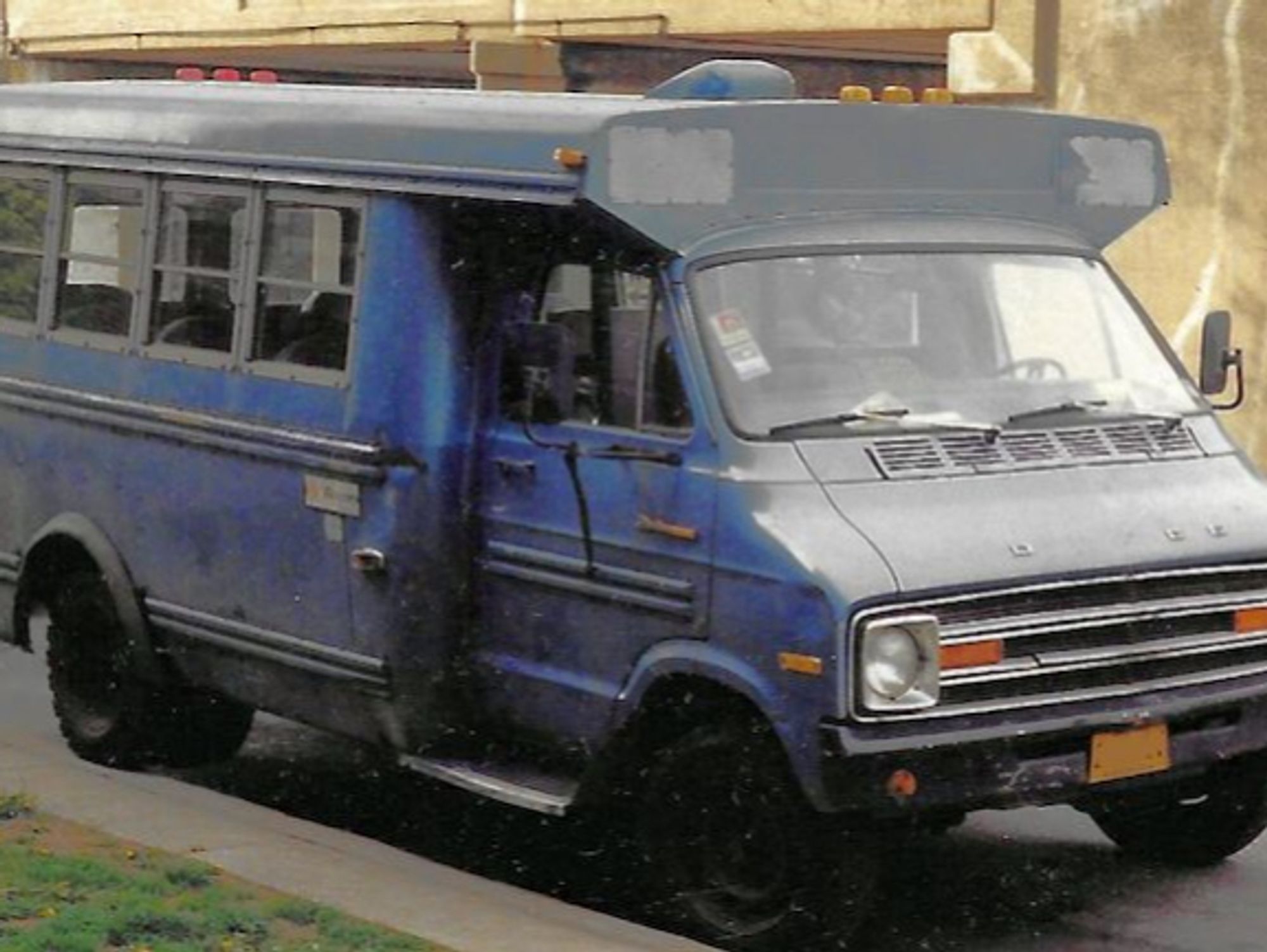 Image of a old, small blue school bus parked curbside in Chicago.