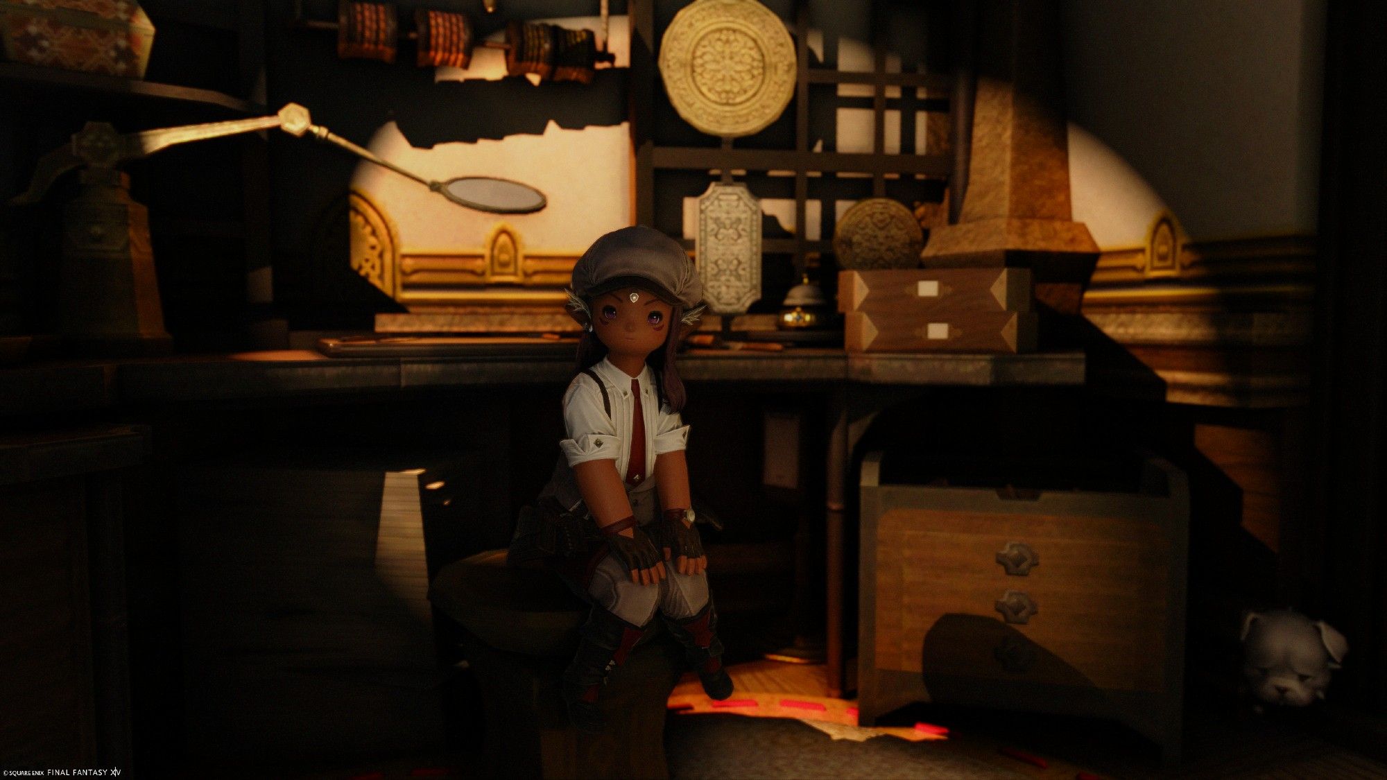 Brown skinned lalafell in a warmly lit room. The jewelry smithing table behind her. She is wearing white and grey clothing and a newsboy hat.