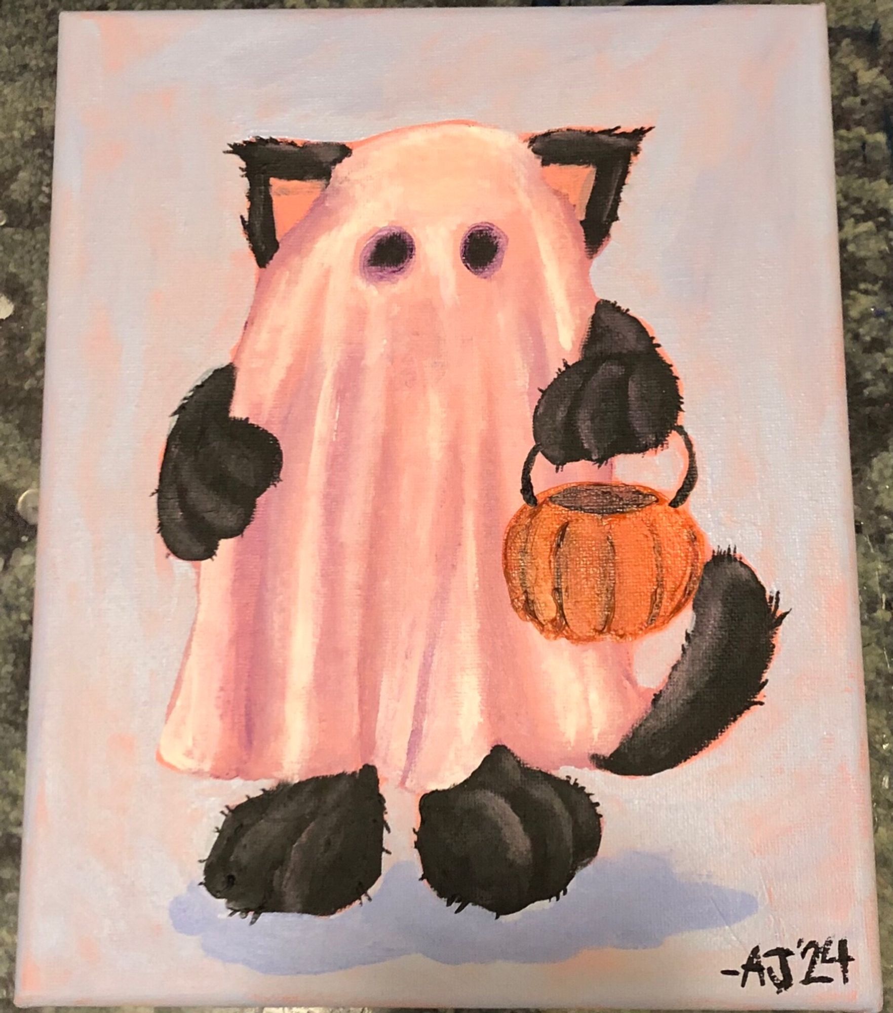 A black cat standing on its hind legs, wearing a sheet with eyeholes as a ghost costume is looking at you while holding a pumpkin shaped bucket. The sheet does not cover its four paws, tail or ears.