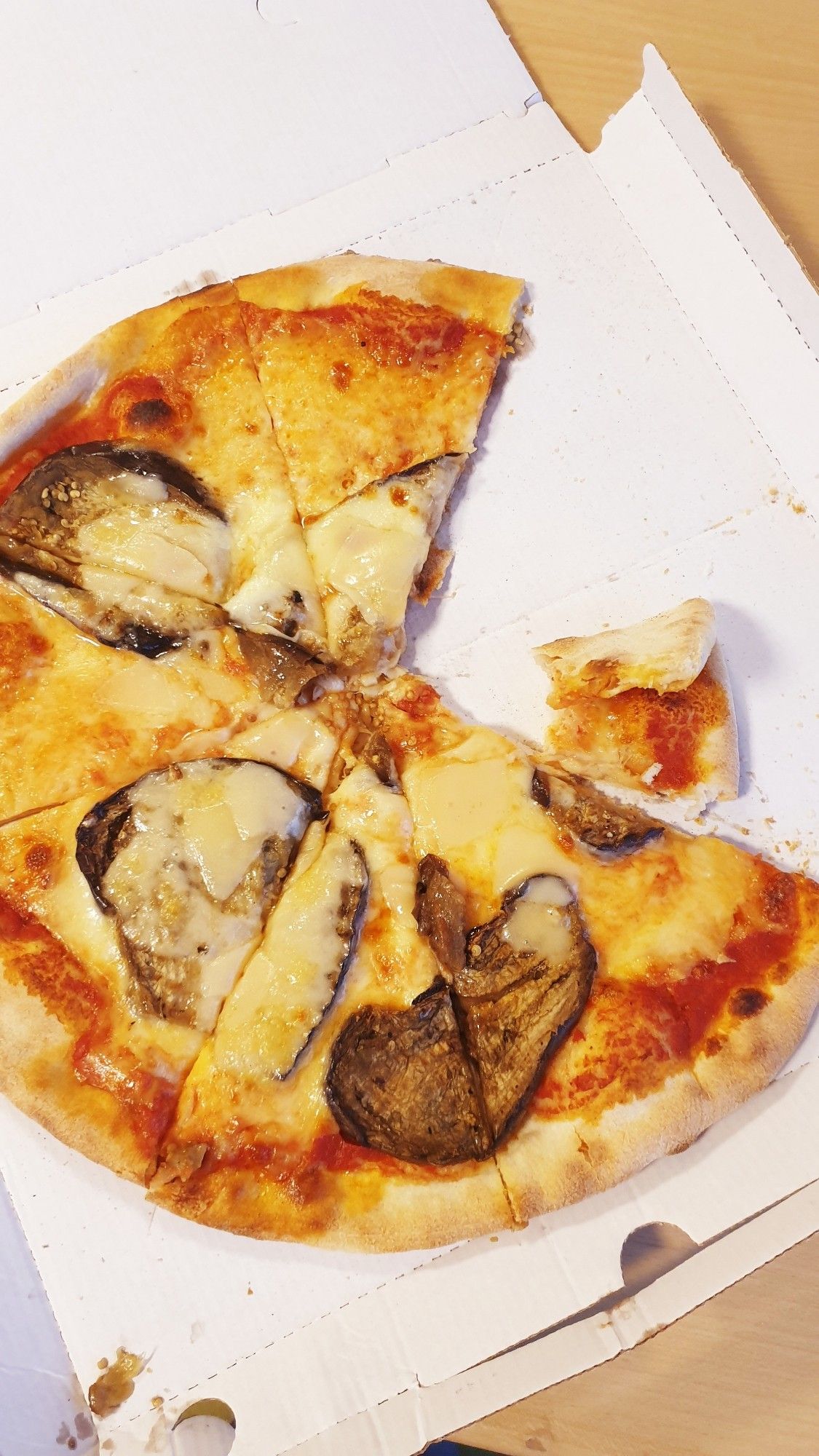 mit melanzane belegte pizza, zwei stück schon gegessen, im karton