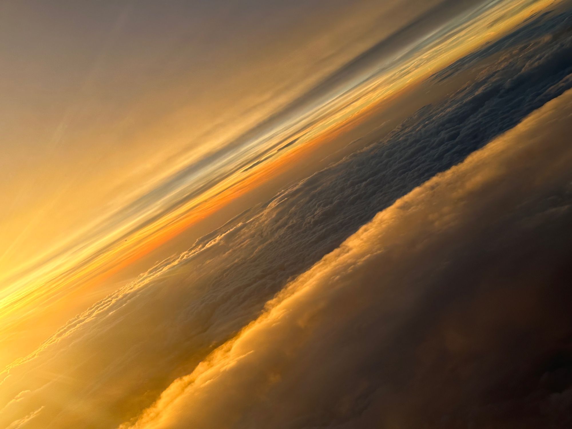 Sonnenaufgang und Wolkendecke.

Links ein heller werdender Sonnenaufgang, der sich nach rechts durch die verschiedenen Ebenen der Wolkendecke kämpft.

Könnten auch Wellen am Strand mit Blick gen Horizont sein.