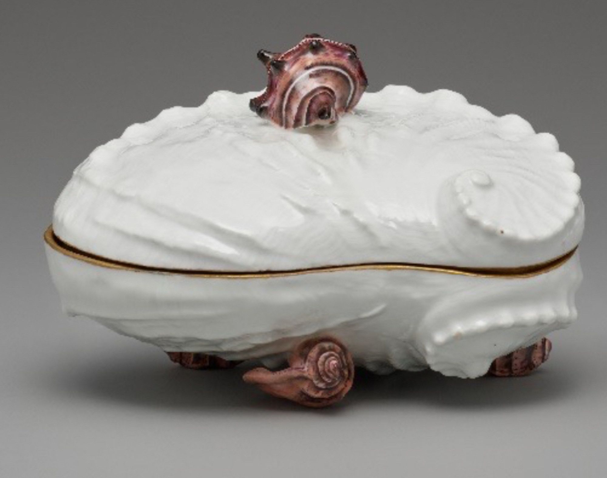 White porcelain mollusc shell, gilt around its closed edges, with a small purple snail perched on top and three below