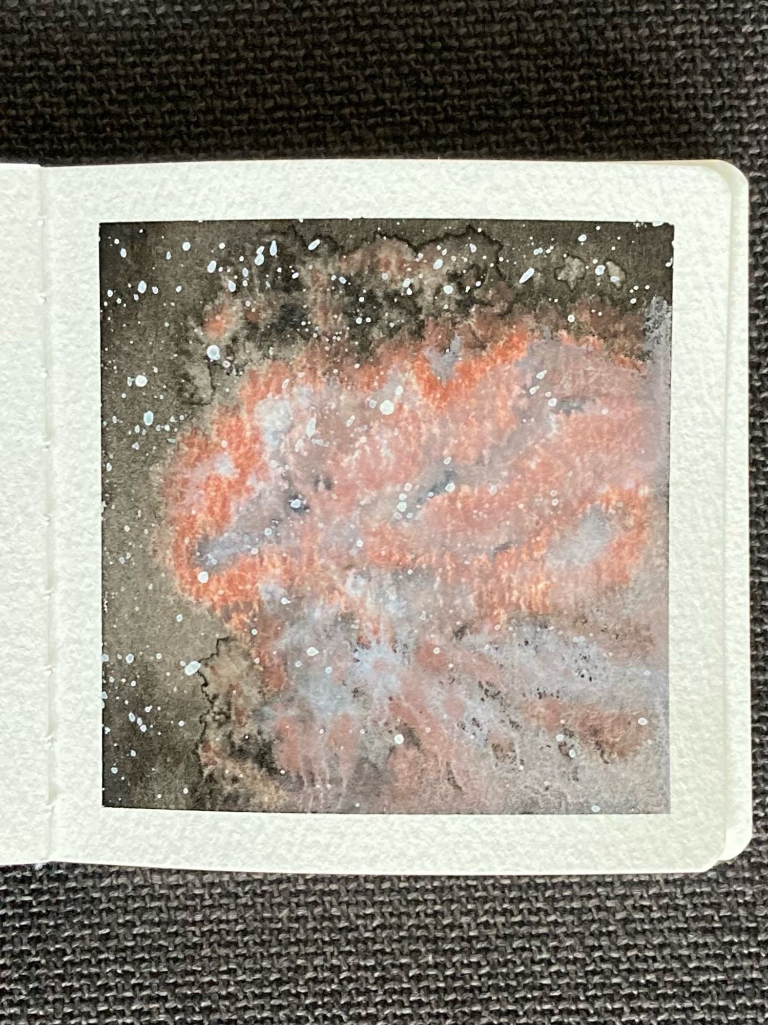 A watercolor painting of a nebula in space. A pale blue-grey cloud of gas is tinged with a reddish orange along its edges. Surrounding the nebula is the vastness of space, dotted with stars.