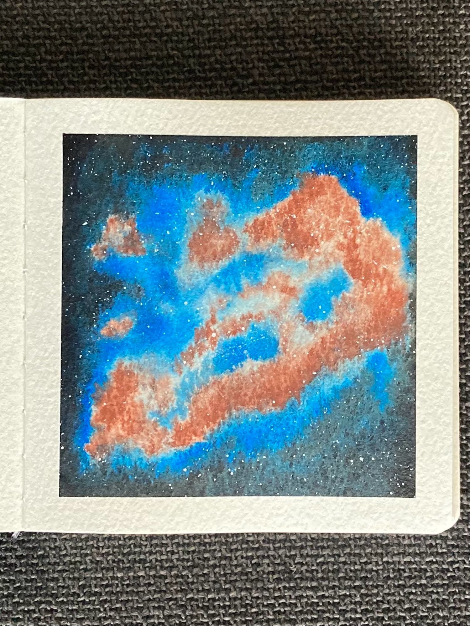 A watercolor painting of a nebula in space. The nebula is an irregular shape spanning from the bottom left up towards the top right. Its reddish brown clouds are surrounded by a blue glow that fades into black. Stars are scattered throughout.