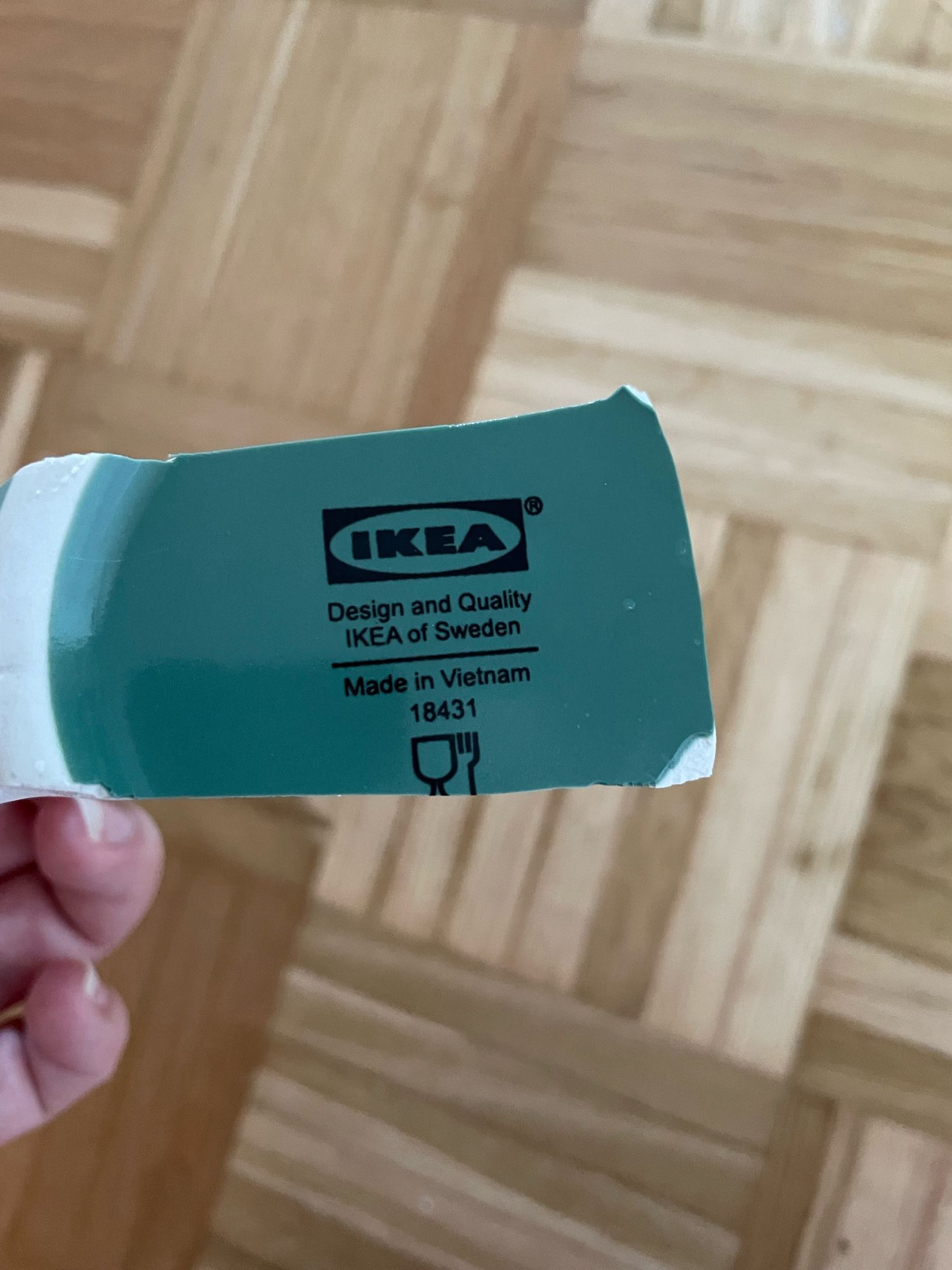 Ich halte eine Scherbe des Bodens der Schale. Es ist ein dunkles Türkis. Darauf steht der typische Ikea-Aufdruck:

IKEA
Design and Quality
IKEA of Sweden
Made in Vietnam
18431

Und darunter als Zeichen ein Weinglas und eine Gabel.