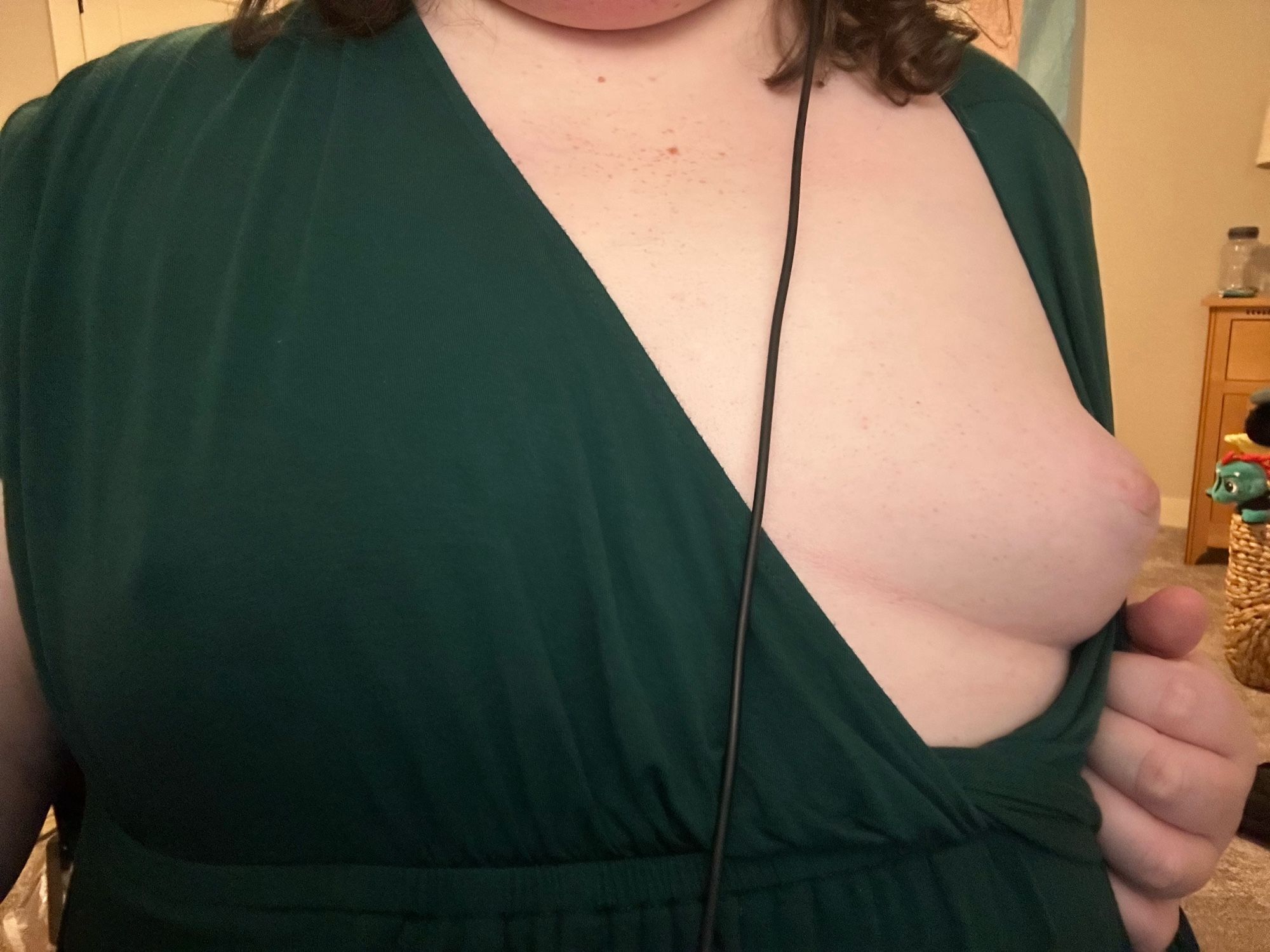 Amelia wearing a green dress and pulling it down to reveal her titty