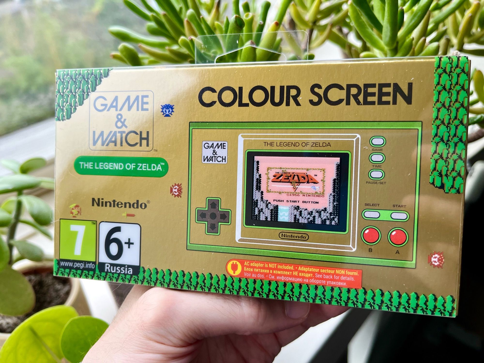 Photo of a Game & Watch “The Legend of Zelda” Color Screen edition. There are colorful Octoroks, walls, and Link sprites from the game on the plastic sleeve.