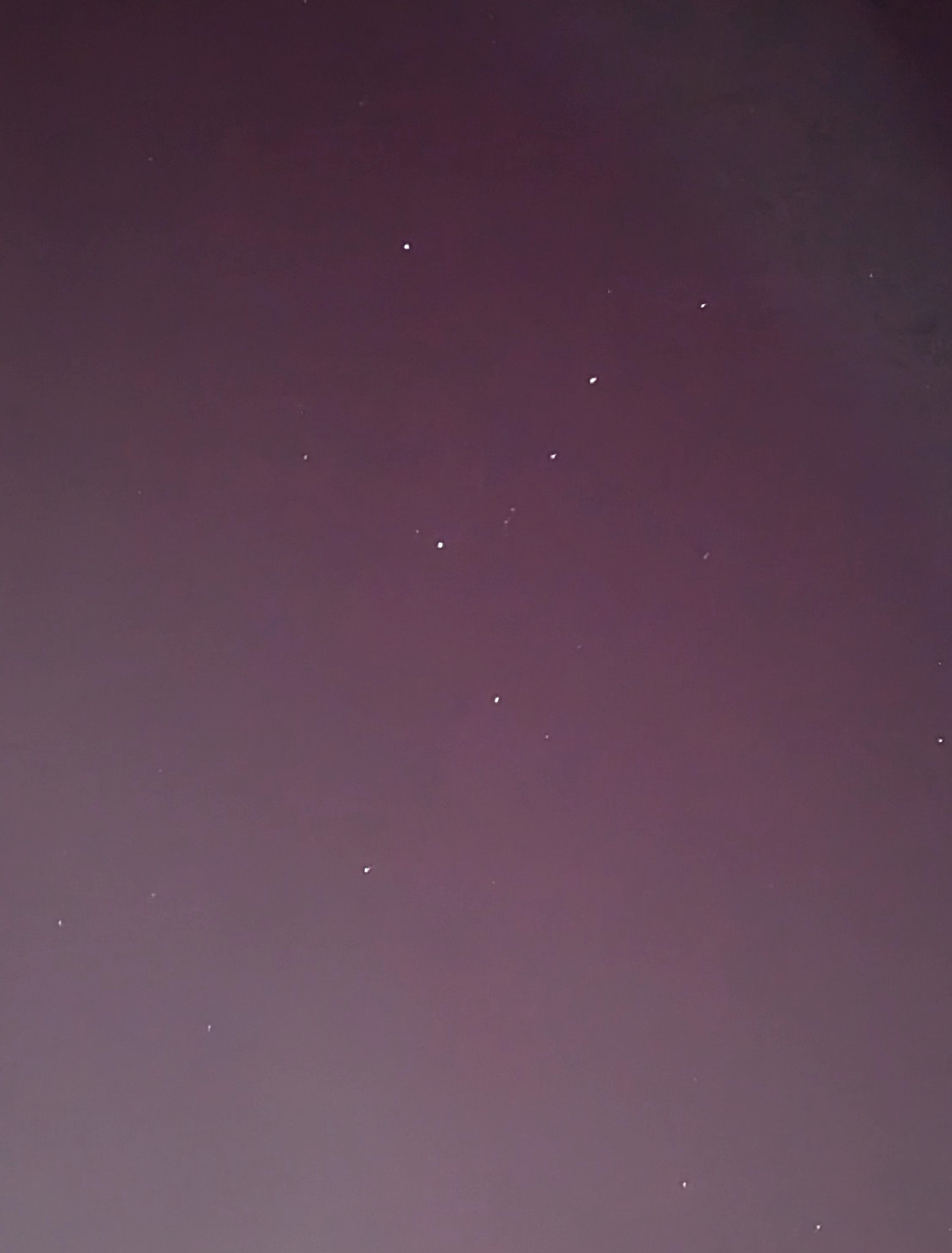 Cropped image of the sky with some stars and pink from the northern lights