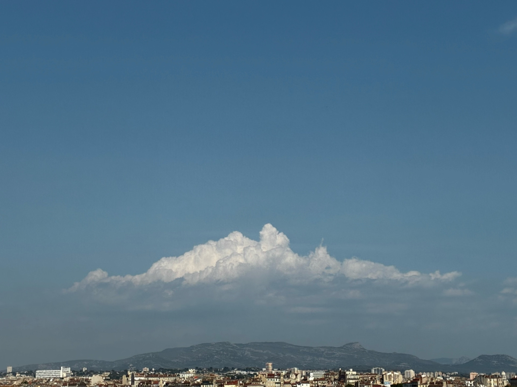 City. Mountain. Clouds.  Blue Sky.