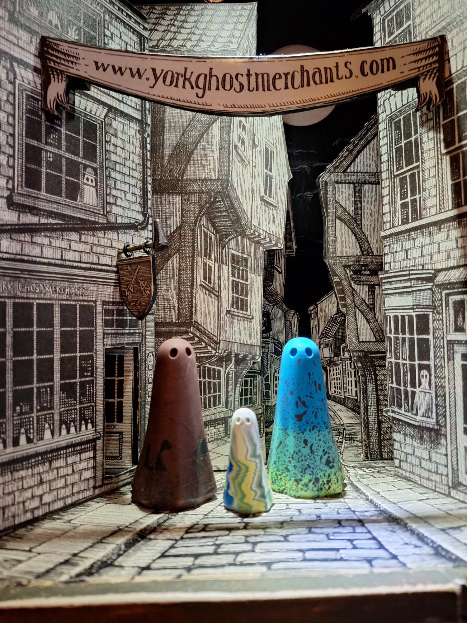 Little colourful handmade ghost figures in a paper scene with www.yorkghostmerchants.com on a banner