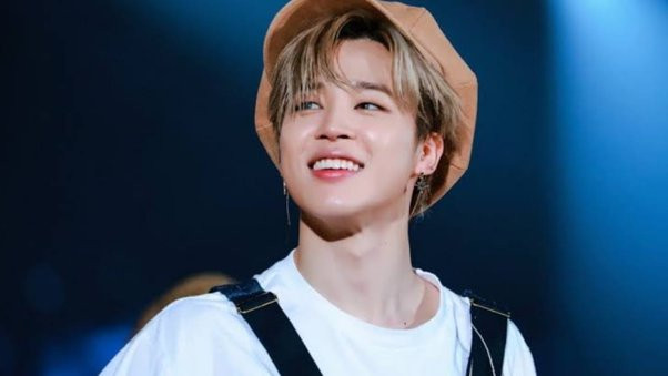 Park Jimin in a white t-shirt and black overalls from about the shoulders up. He is wearing a tan cap, looking up and to the left while smiling. As always, he is absolutely gorgeous. Smile would 10/10 cure your depression.