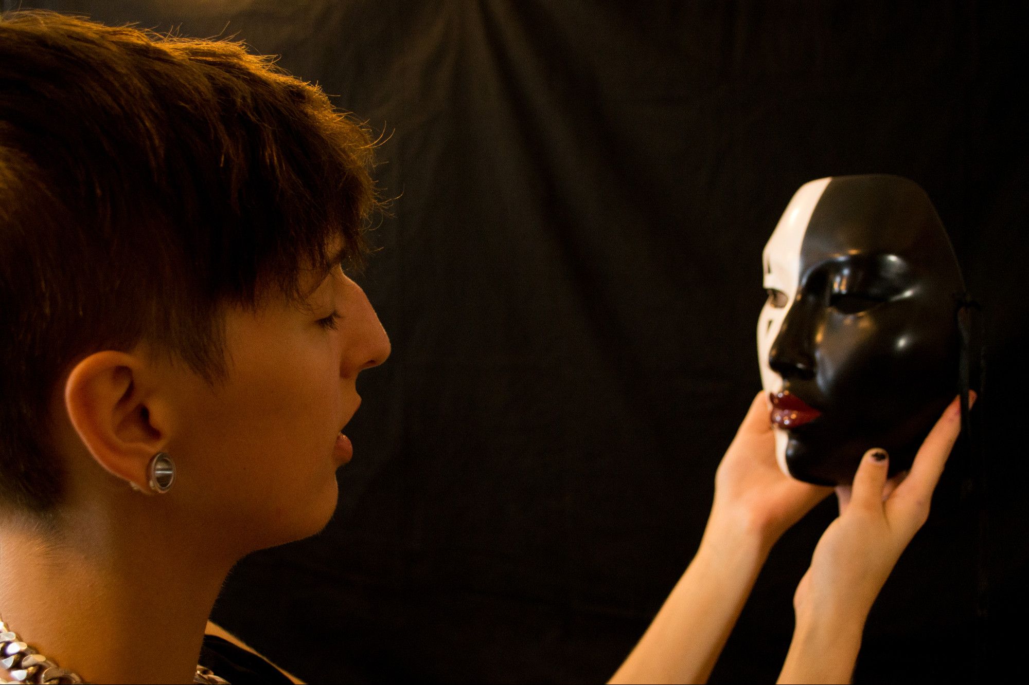 a skinny young white woman holds a mask up in front of her self, communing