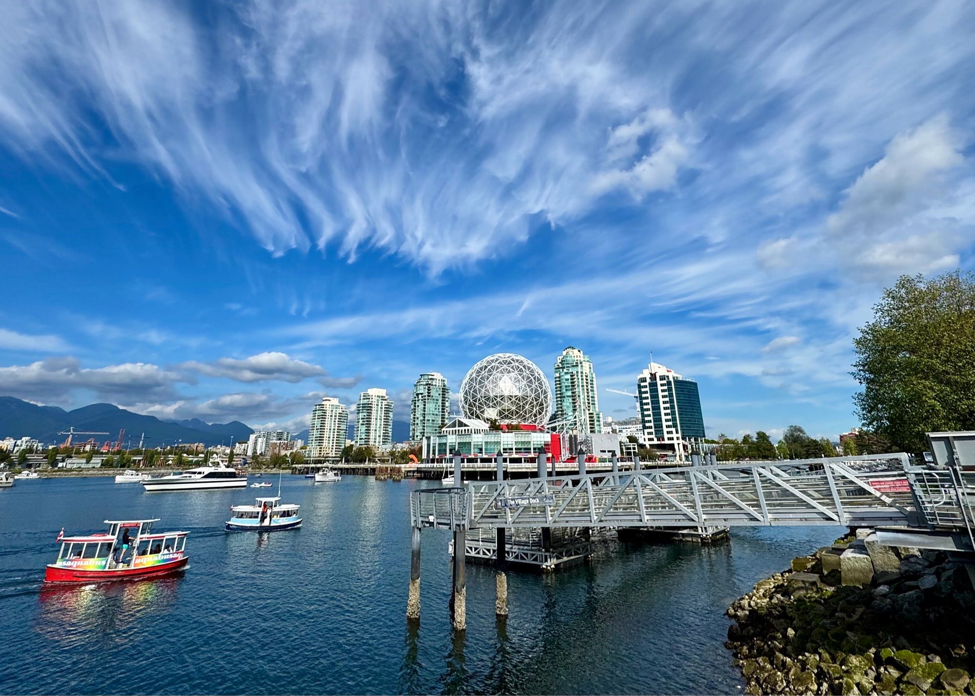 wispy cirrus clouds painting the skies above Vancouver BC’s Science World & False Creek