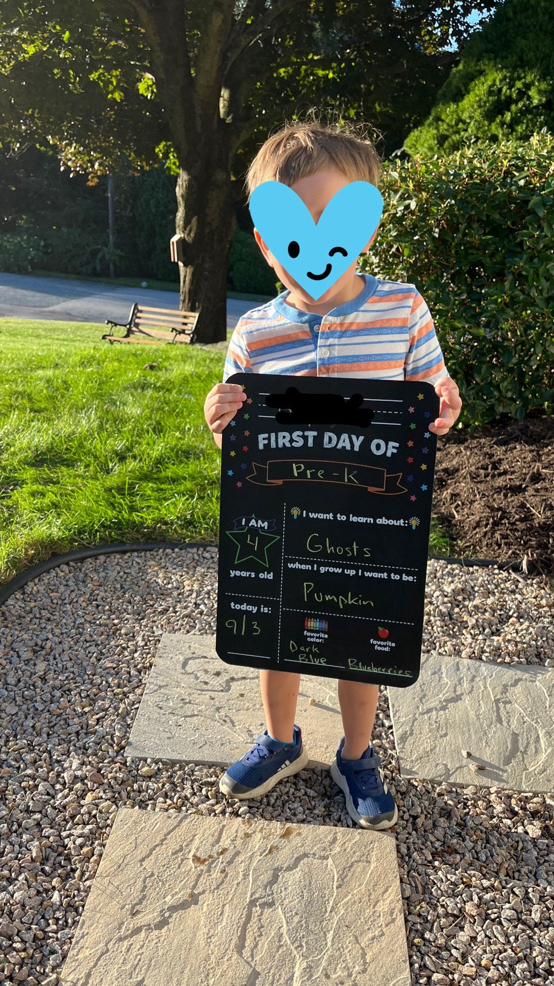 Child holding first day of school chalkboard, where “when I grow up I want to be” is filled in with “pumpkin”.