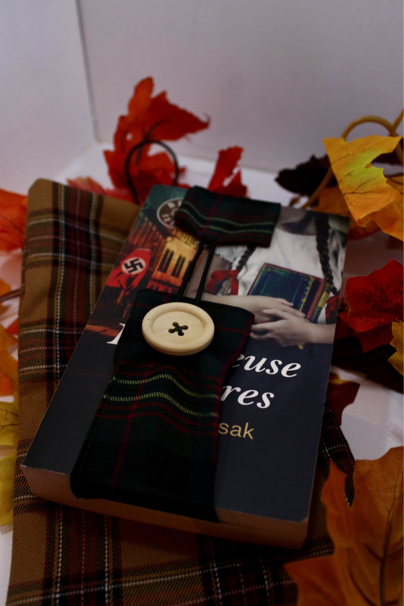 Pochette cousue dans un tissu tartan jaune et rouge. Un livre est posé sur la pochette, avec un marque pages réalisé dans un tissu tartan dans les tons vert sapin et rouge