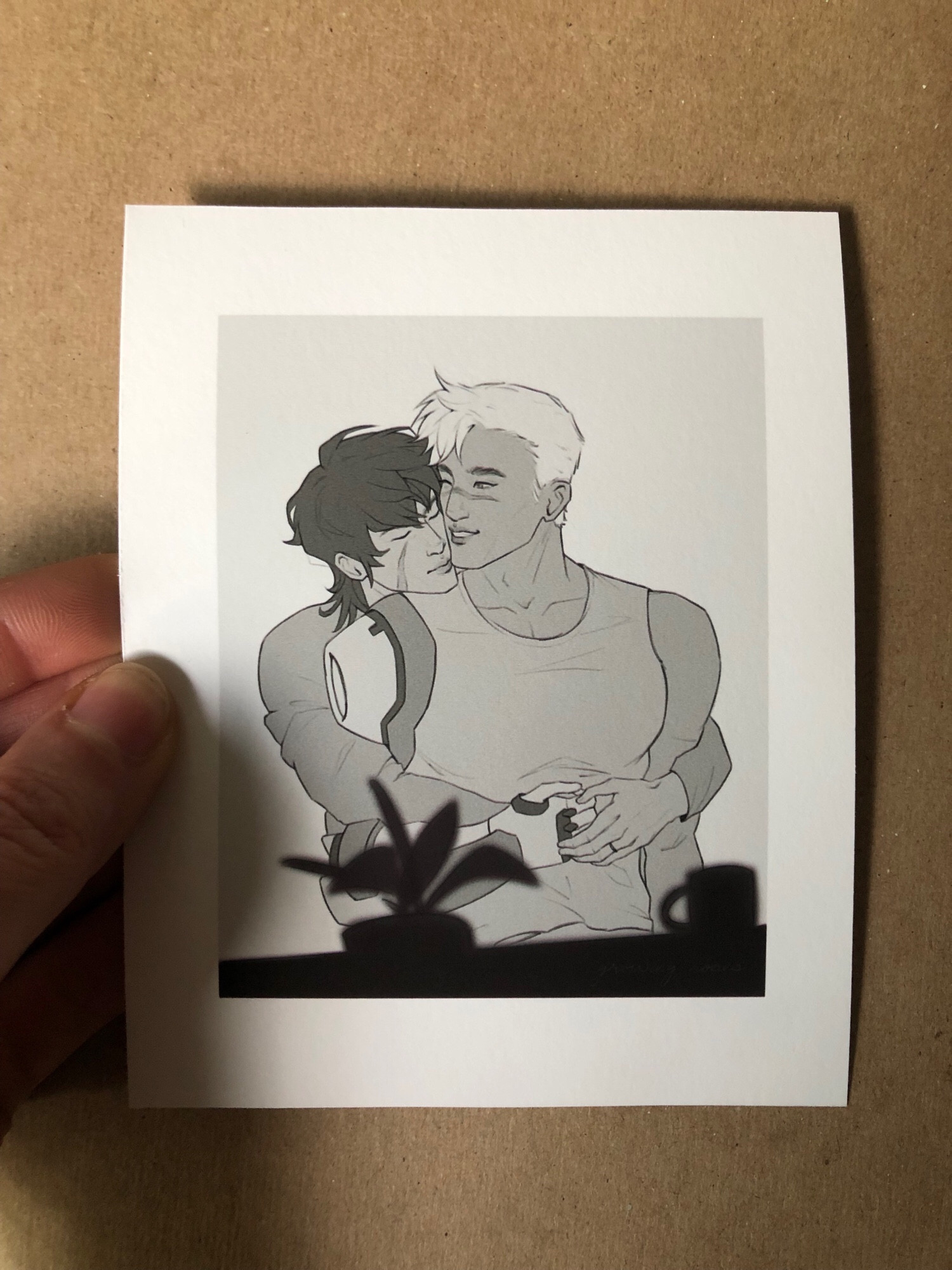 a hand holding a small print of black and white sheith fan art.