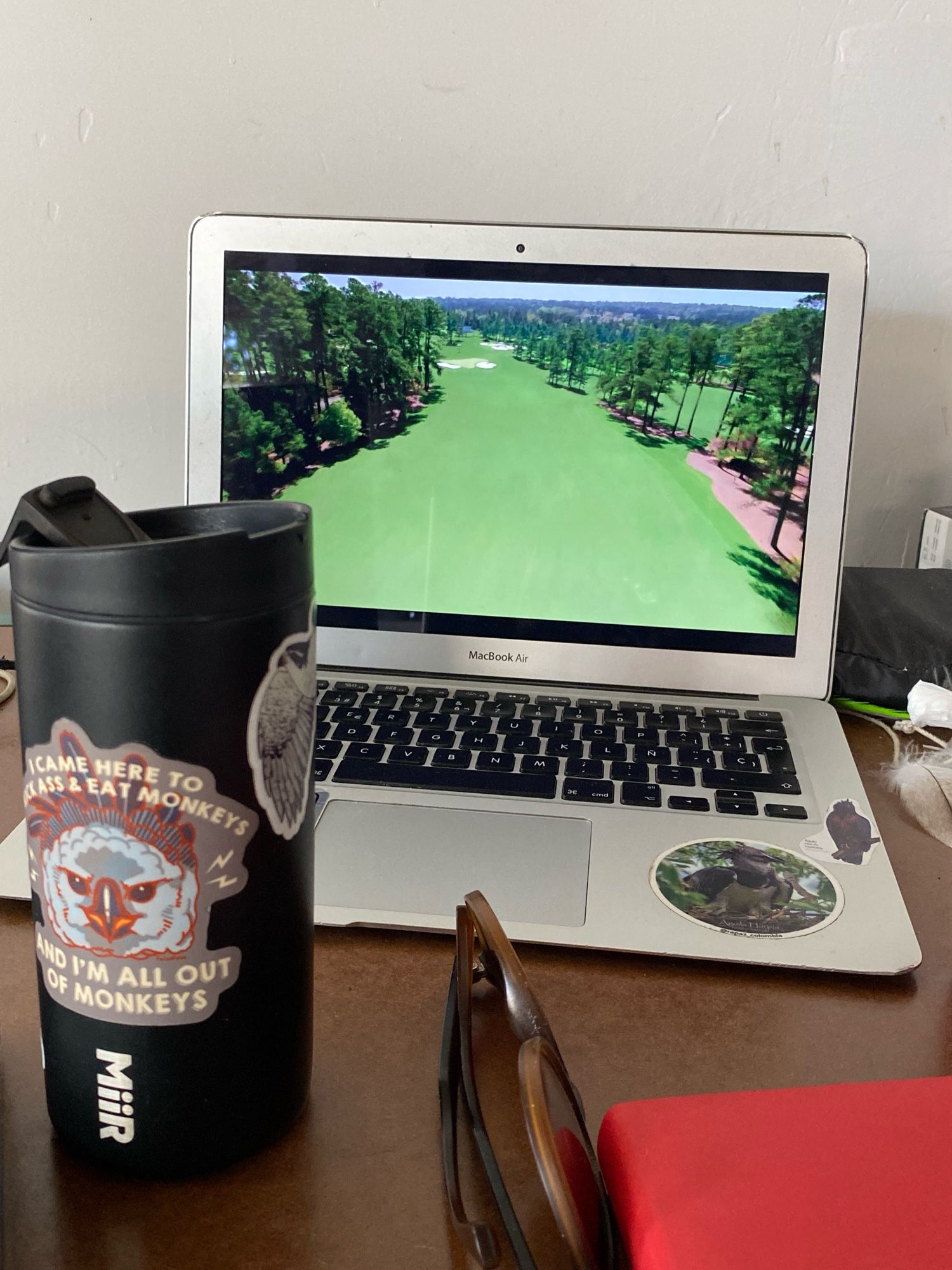 Photo of my MacBook streaming The Masters and my travel coffee mug with an amazing Harpy Eagle sticker