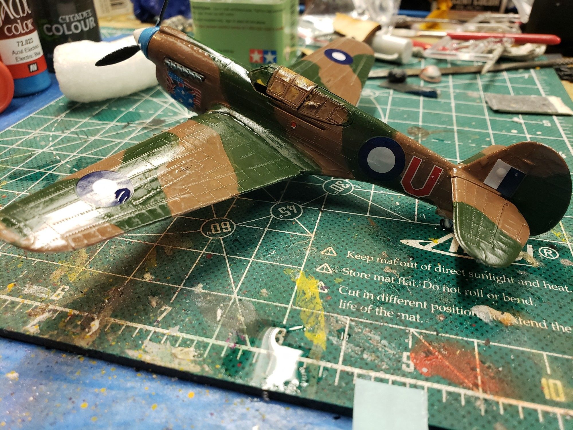 A model of a Kittyhawk Mk IA, in a high gloss rendering of a Second World War Australian Air Force camouflage scheme in dark earth and foliage green.  The markings on the upper wings and left side fuselage have been applied.