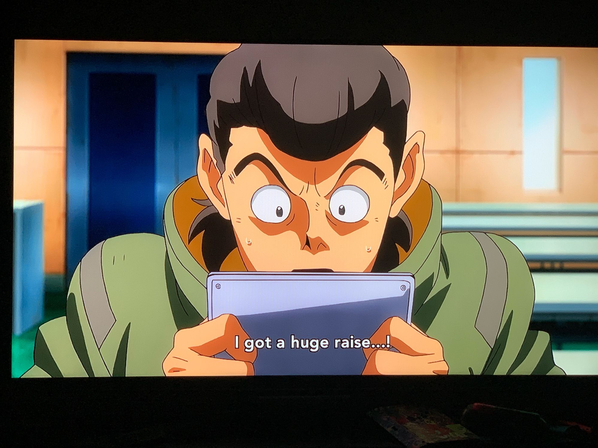 Shot from Mobile Suit Gundam: Iron-Blooded Orphans of a man staring bug-eyed at a data pad, exclaiming with understandable surprise "I got a big raise...!"