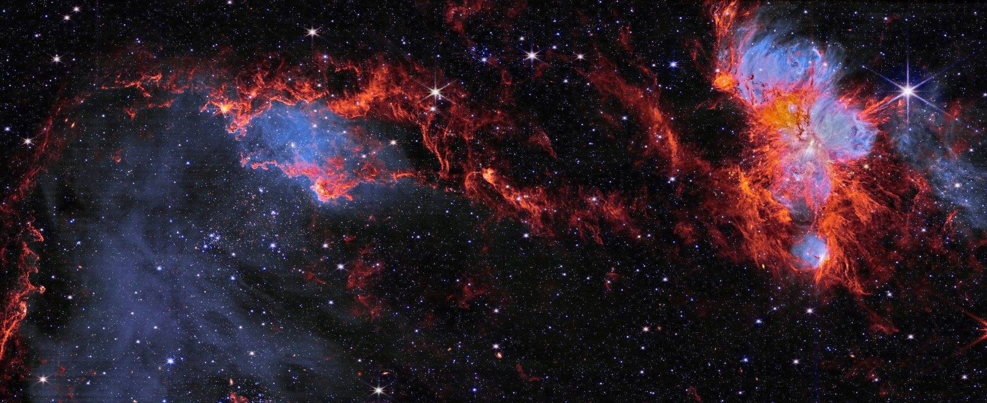 A vibrant cosmic landscape of the N79 region, captured in infrared light by the NIRCam instrument. The image showcases a dazzling array of stars, nebulae, and interstellar clouds, painted in hues of red, blue, and white