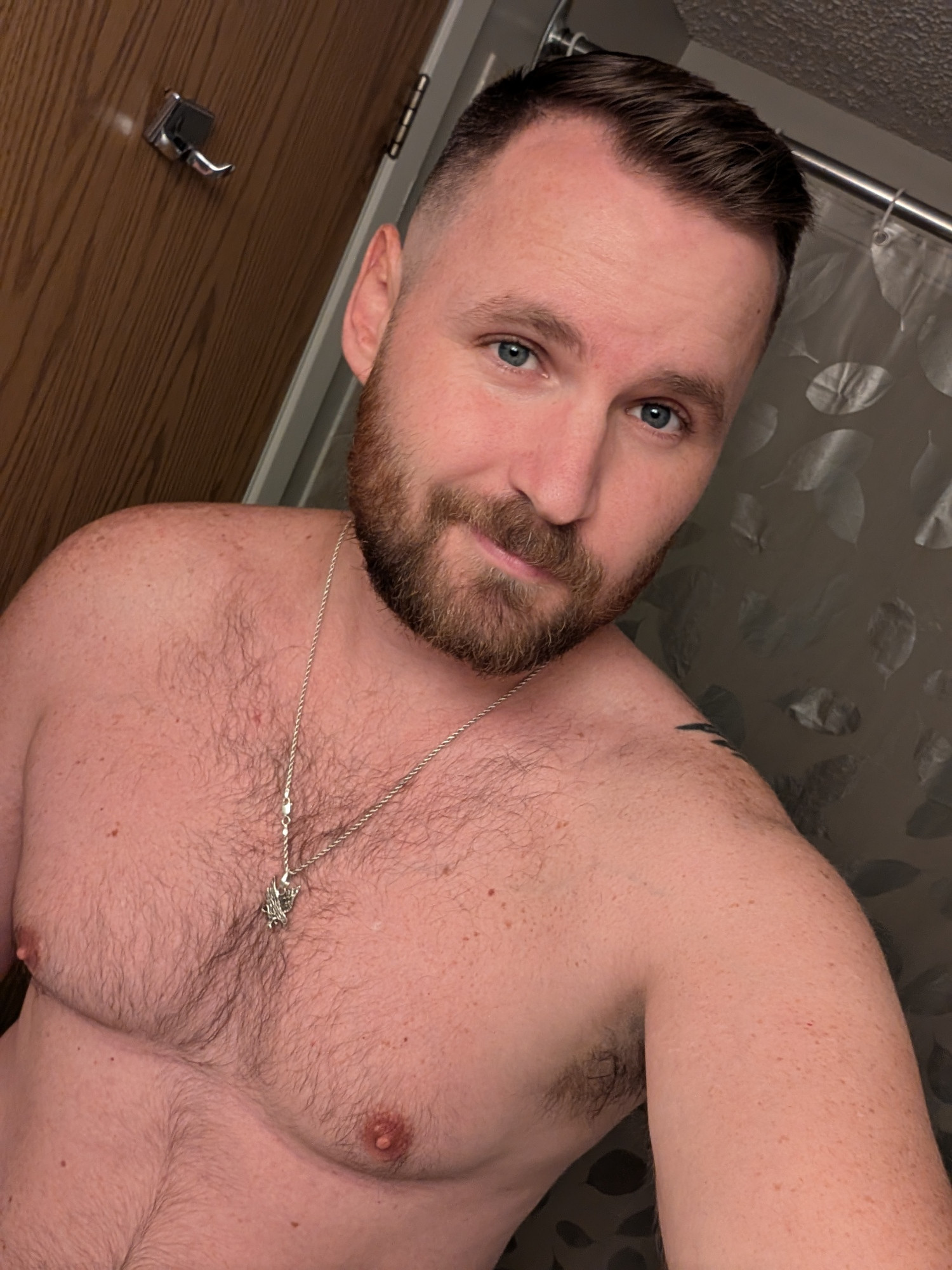 A selfie of my new hair cut. I'm shirtless and have a silver chain around my neck