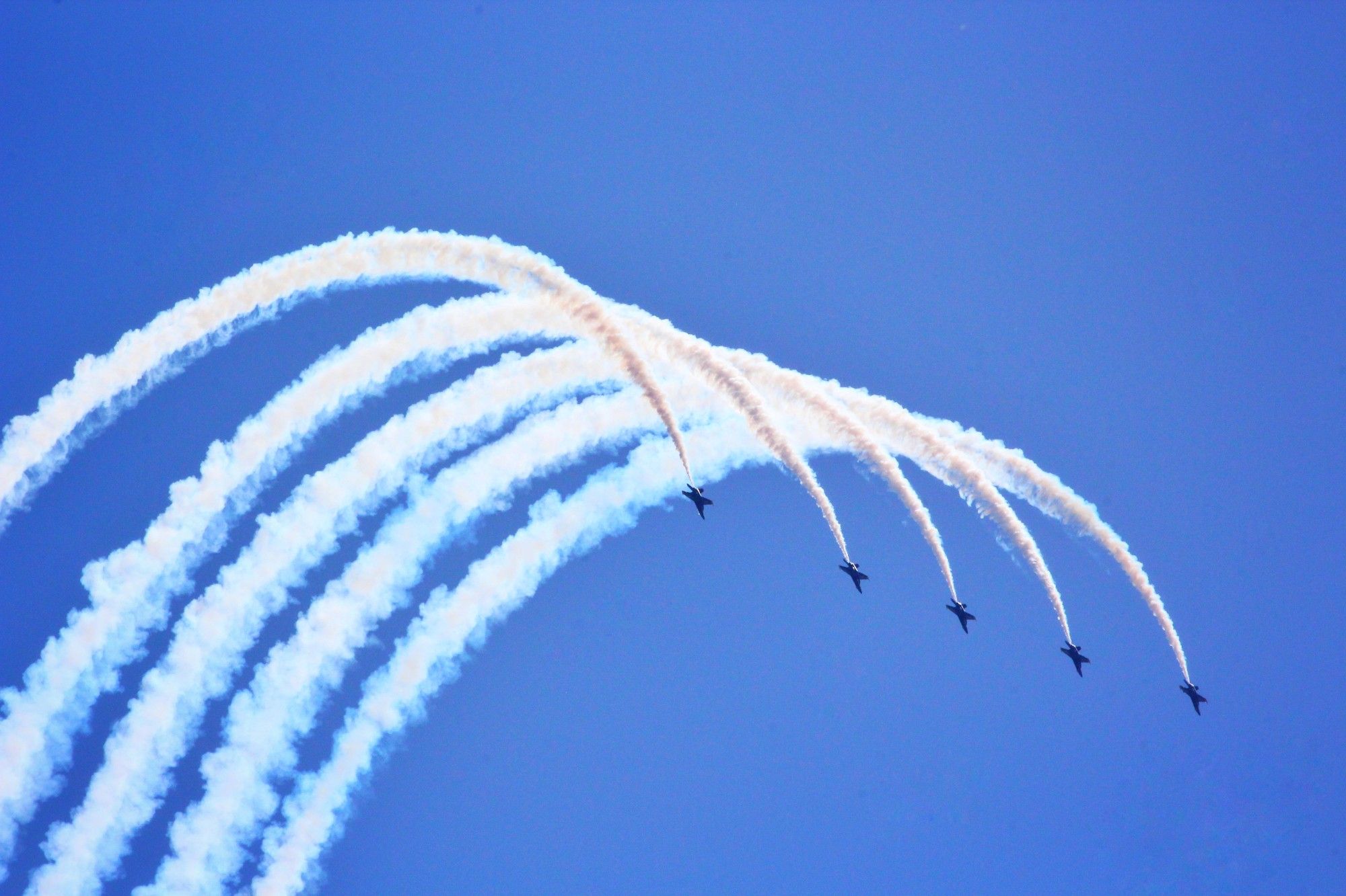 5 Blue Angels flying in formation with white smoke