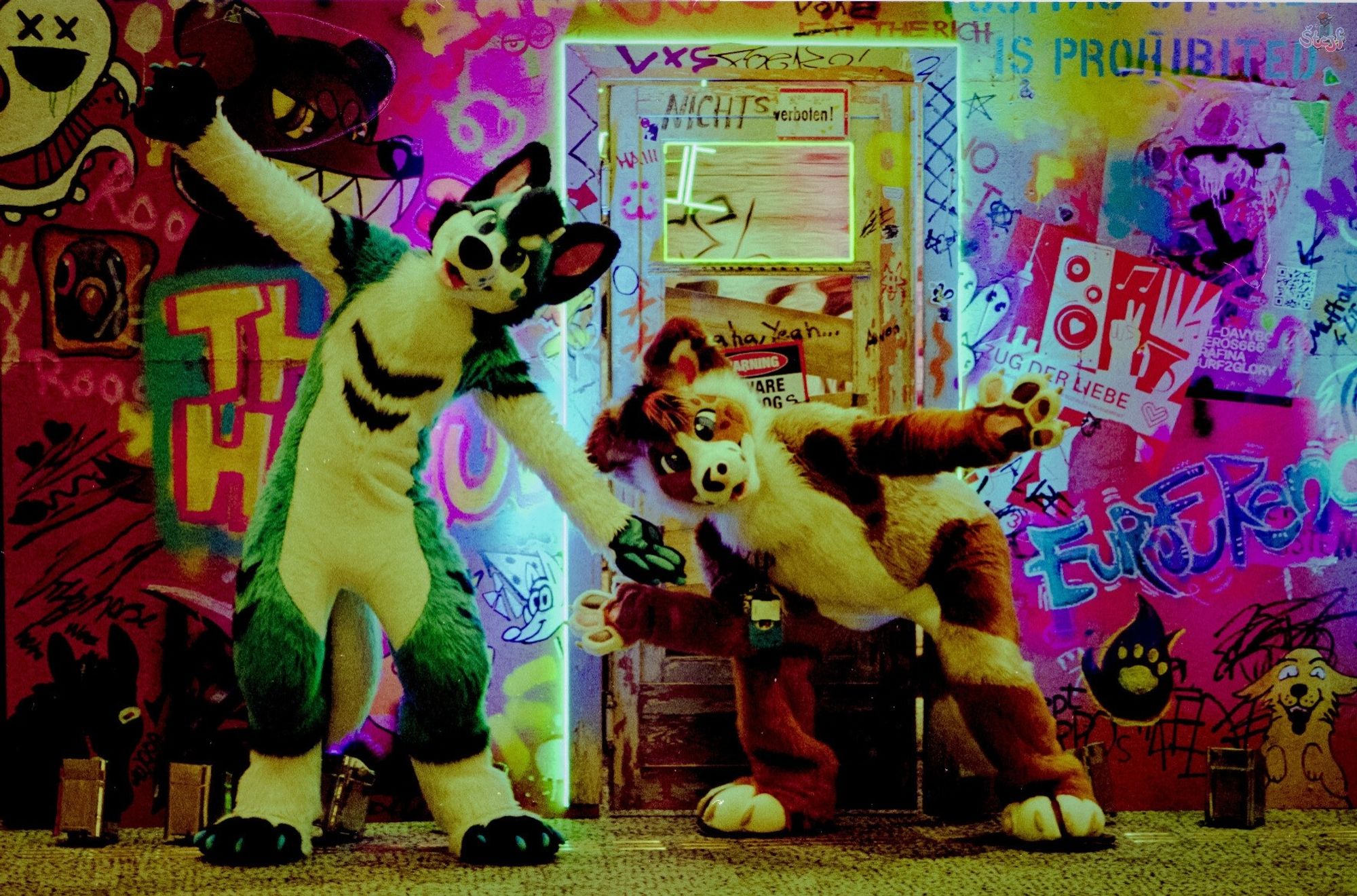 two suiters, Exi on the left and Lexie on the right posing in front of a "wall" filled with grafiti. It's the outside of EF's Photobooth