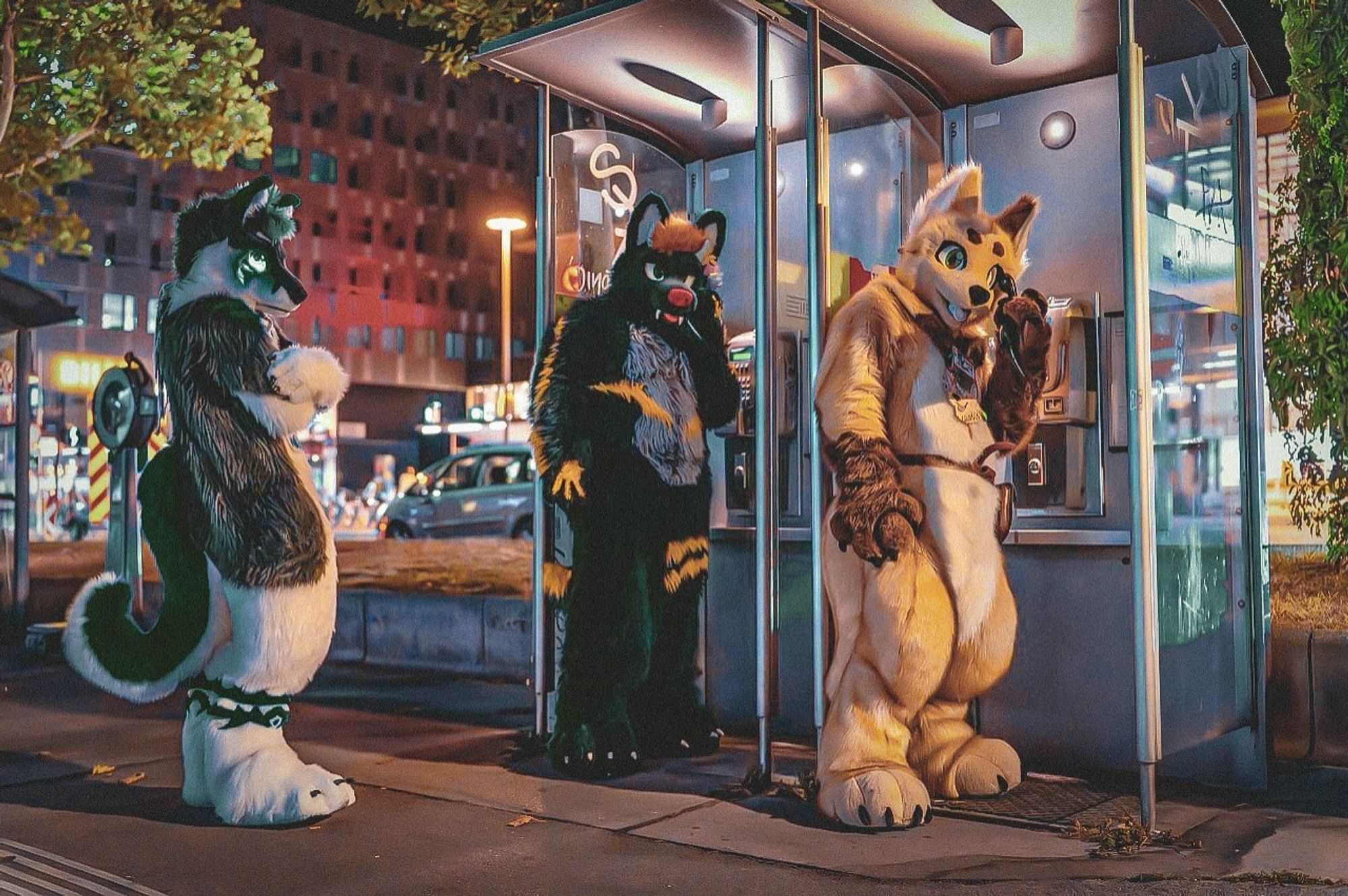 A picture of three Fursuiters at night.
Two of them are using a public coin phone, while one is waiting for one of the other two to finish.