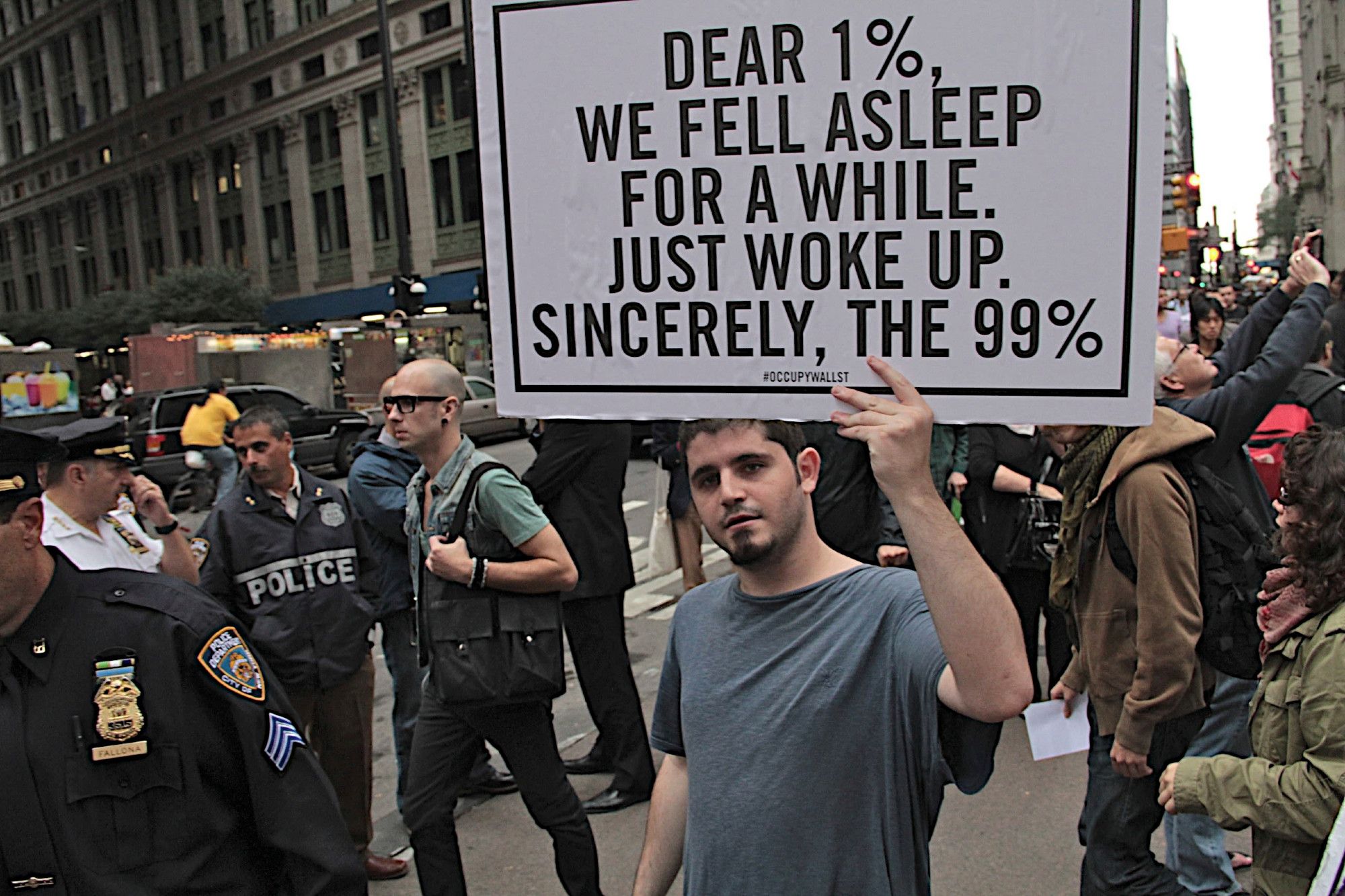 Ein Mann hält inmitten einer Demonstration ein Schild hoch auf dem steht:
Dear 1%, we fell asleep for a while.
Just woke up.
Sincerely, the 99%
#occupywallst