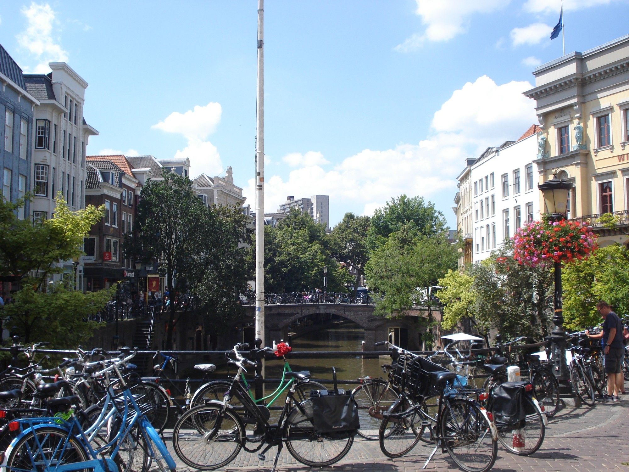 Utrecht centre. Shows a canal running through, which is below the gound level, and a bridge in the foreground and the background, with lots of bikes parked all across it.