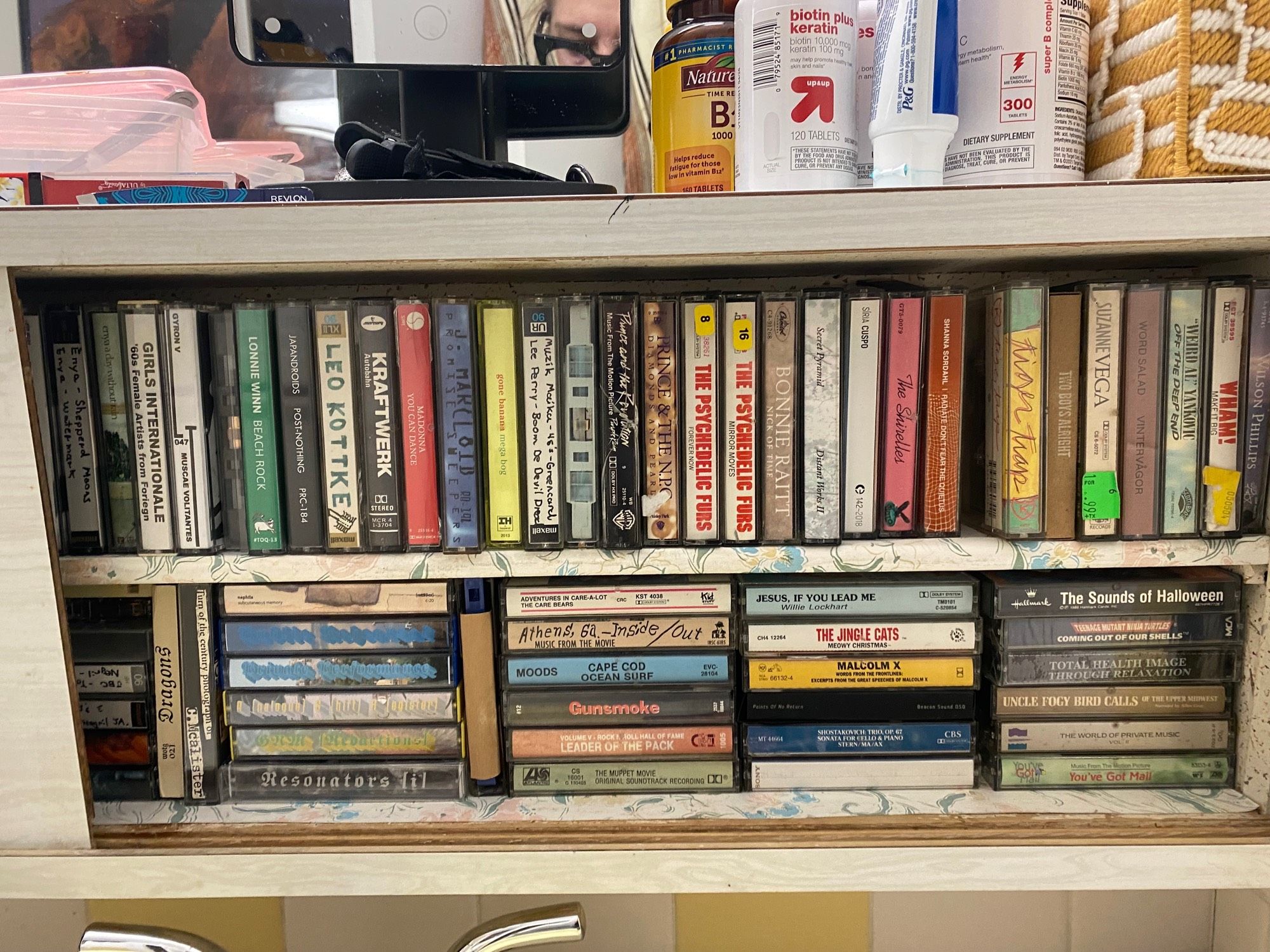 Rows of cassette tapes stored in a bathroom vanity medicine cabinet.