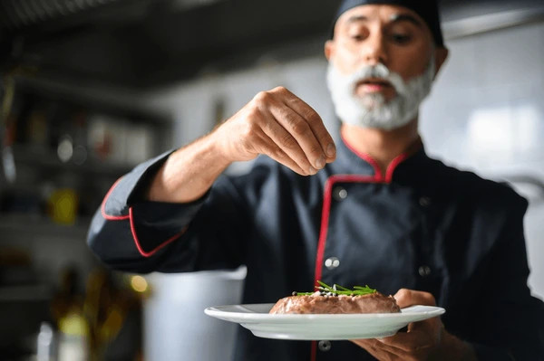Stock photo of a commercial chef holding a dish he just prepared.