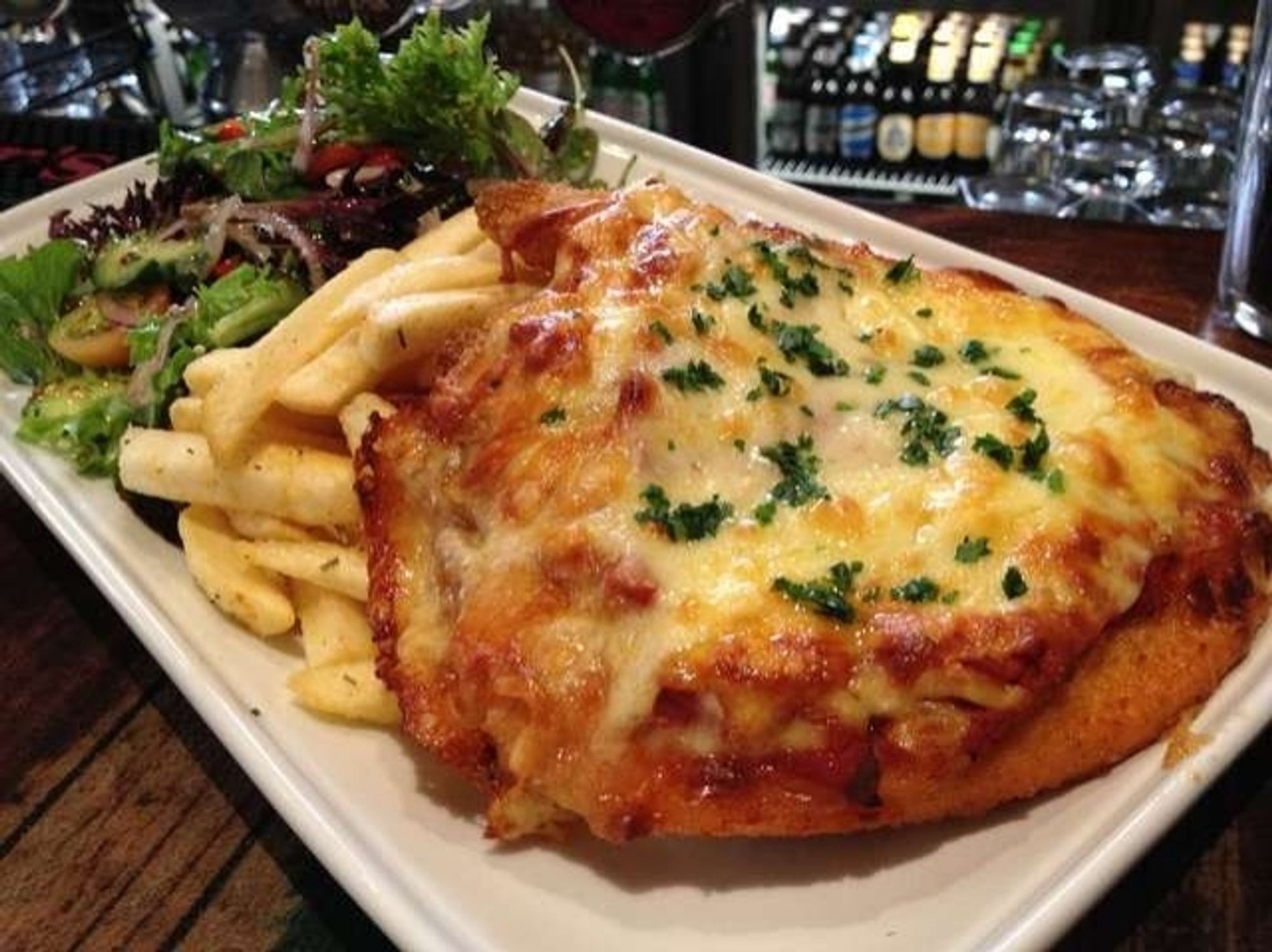 A rectangular plate with a big chicken parmigiana, chips, and a garden salad. Staple of the Australian pub meal scene since forever.