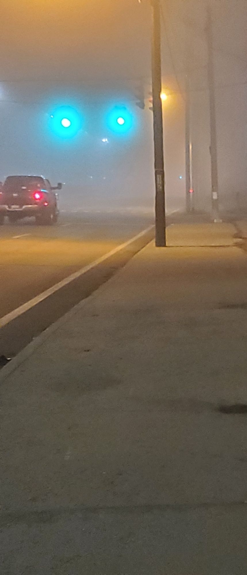 A picture of a very foggy street at night. There is a pickup truck at a stoplight that has just turned green; the lights are blown and hazy because of the heavy fog.

You can faintly see another set of stoplights down the street but they are mostly obscured by fog. Those particular stoplights are about a quarter of a mile away.