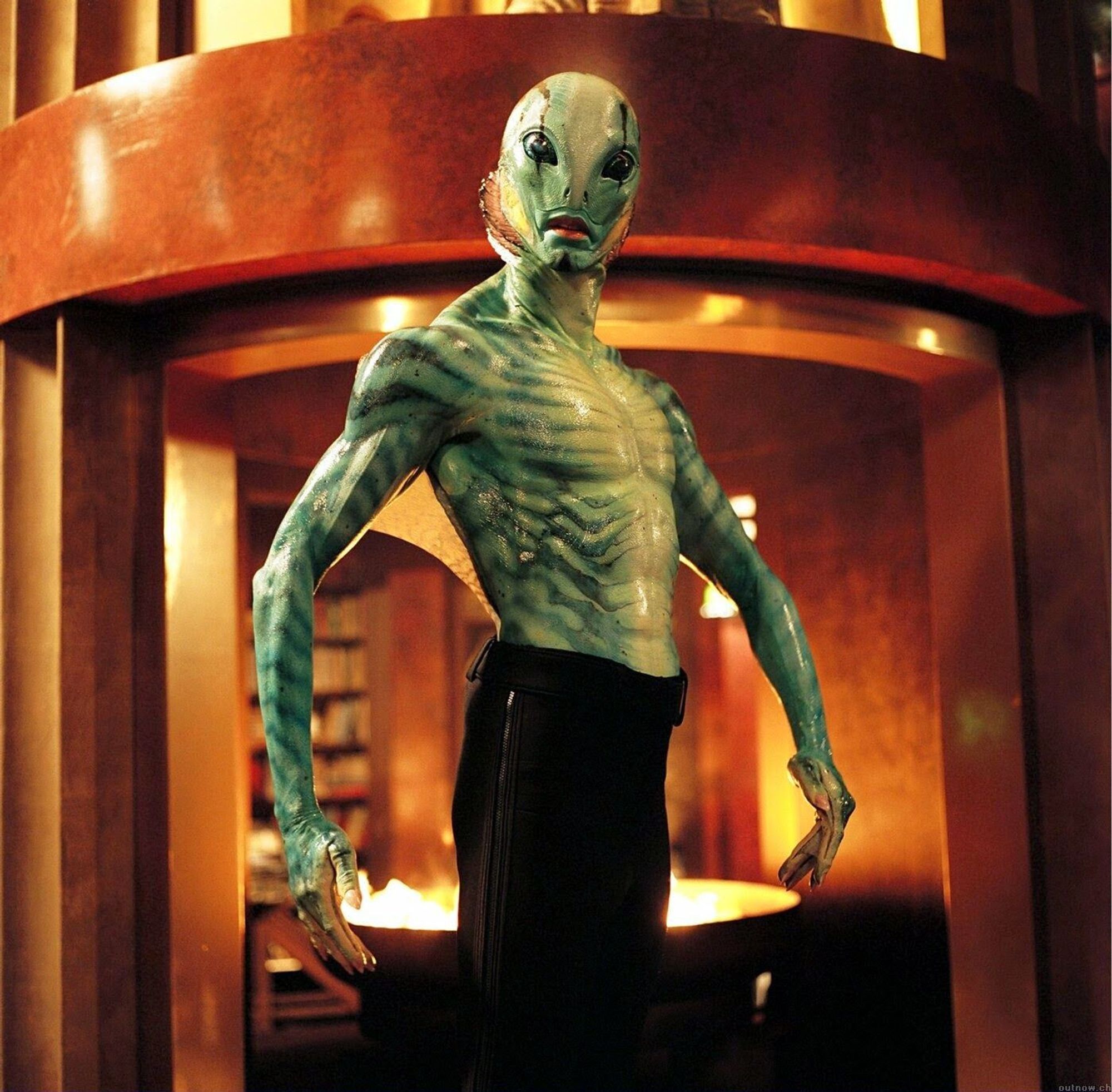 Abe Sapien from Hellboy, standing in front of a firepit while he only has black pants on.