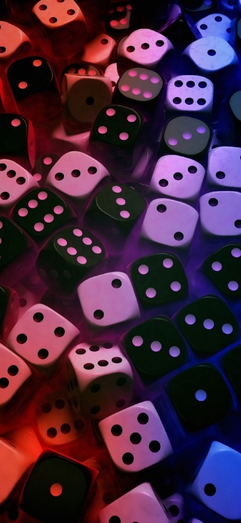 An image of a bunch of black and white colored dice but there appears to be a red/pink/purple like light covering the image.