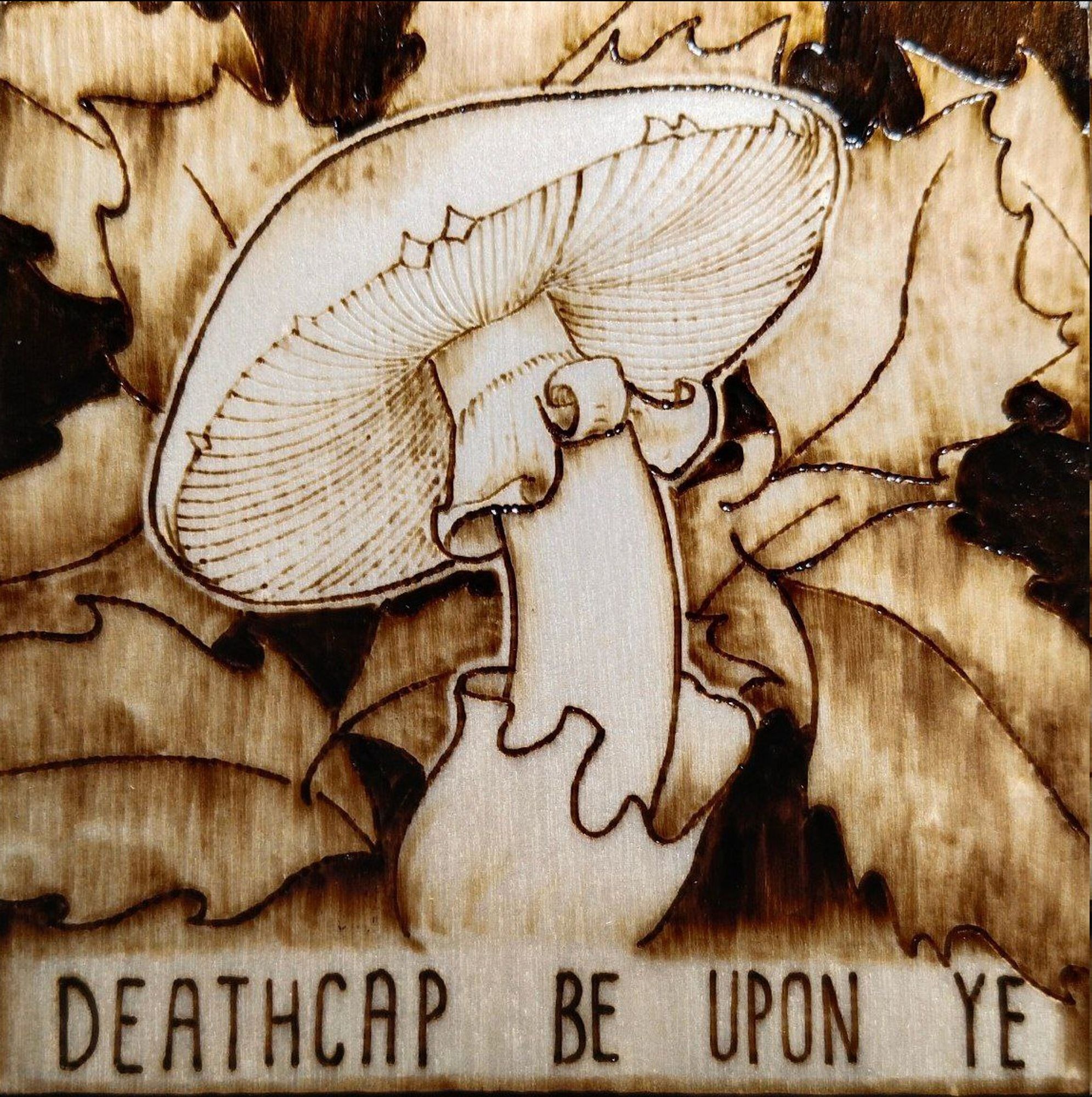 Wood-burning piece of a deathcap among pointy leaves. "Deathcap be upon ye"