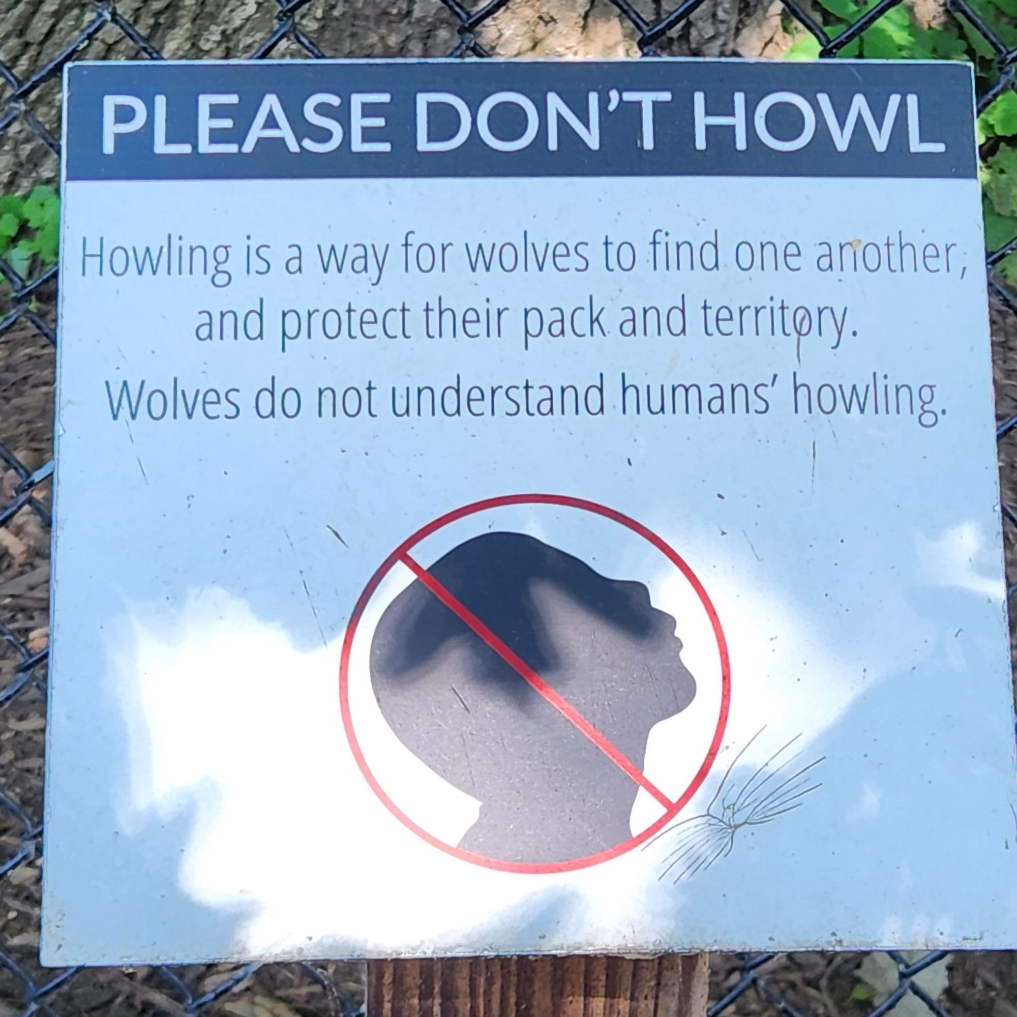 A no howling sign. "Please don't howl. Howling is a way for wolves to find one another and protect their pack and territory. Wolves do not understand humans' howling."