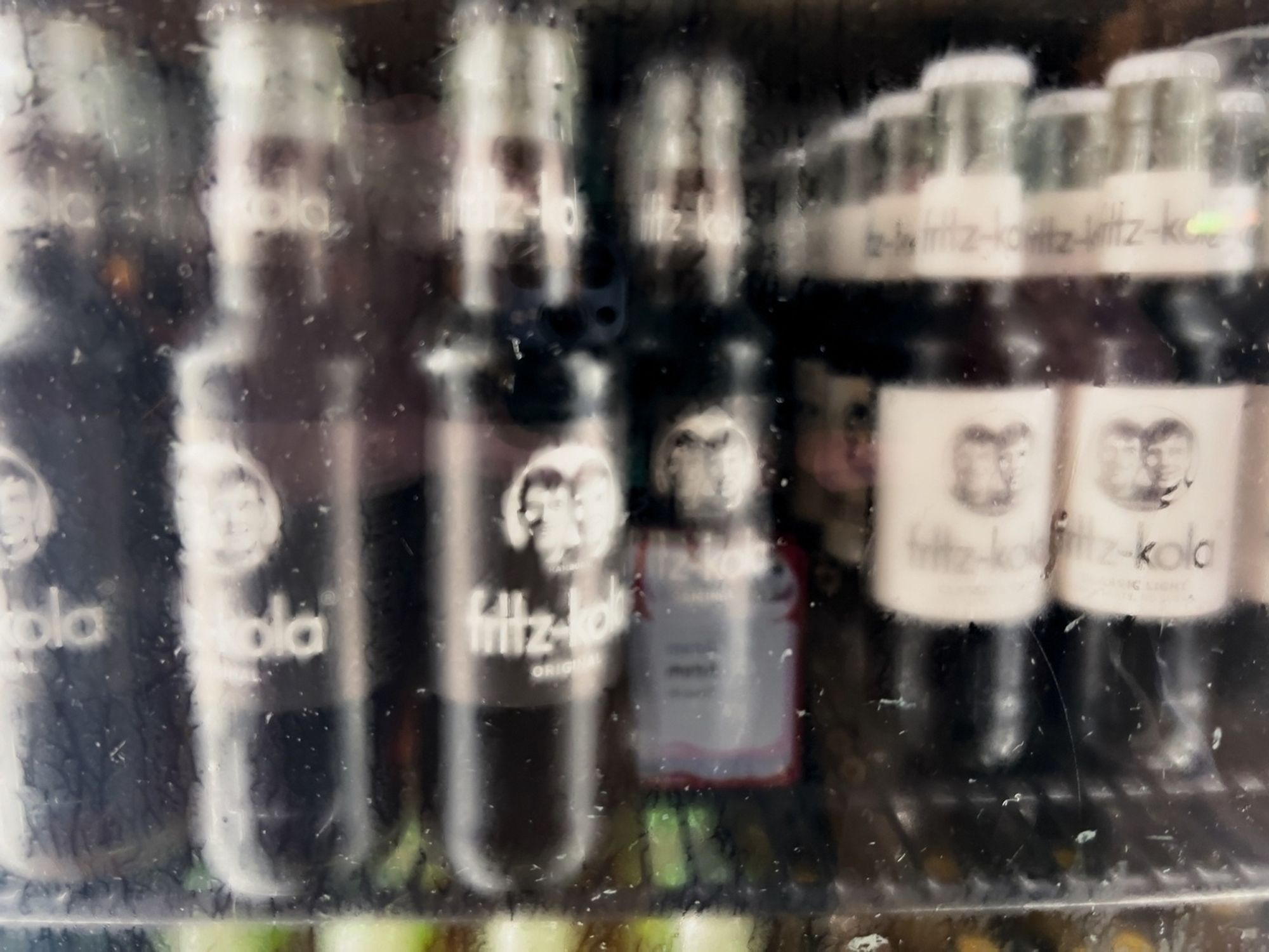 Several bottles of Fritz-Kola are displayed behind a glass surface.