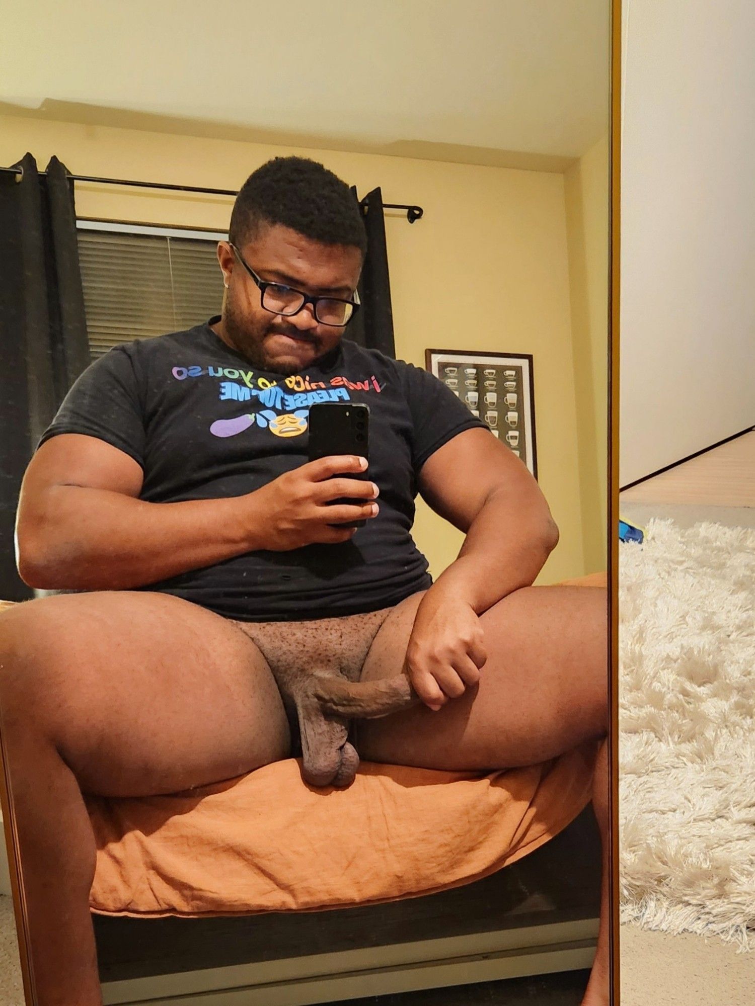 Me taking a mirror selfie. I'm sitting at the edge of my bed with my legs spread wide, and my hard cock in my other hand.