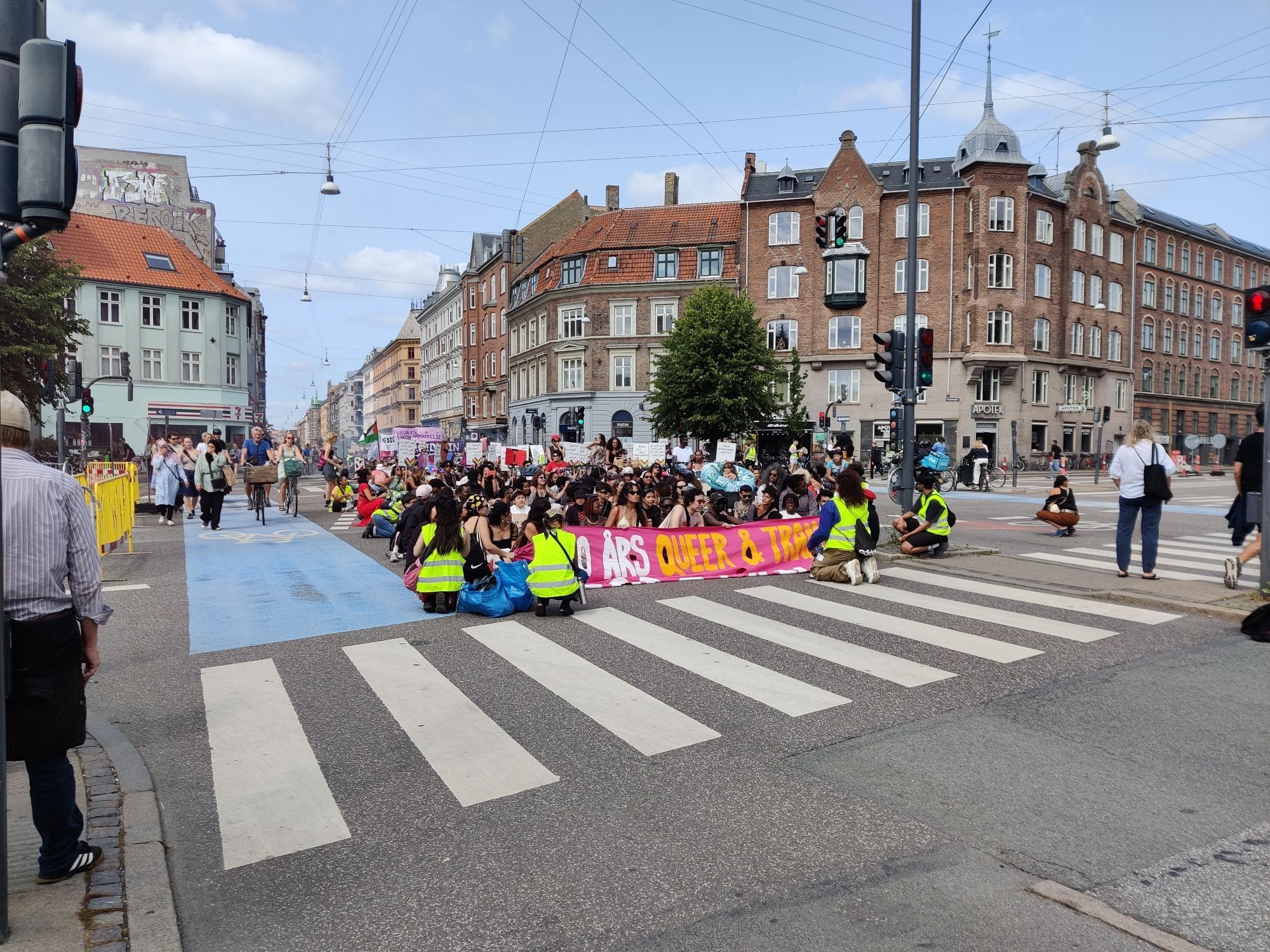 A parade sat in the middle of a junction. The opening banner reads 500 års queer & trans motstand (which means 500 years of queer and trans resistance)